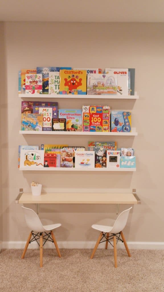 Books on a shel with a desk and two chairs | Basement Playroom 