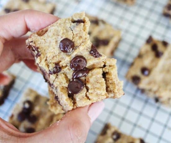 person holding gluten free chocolate chip cookie bar over baking pan