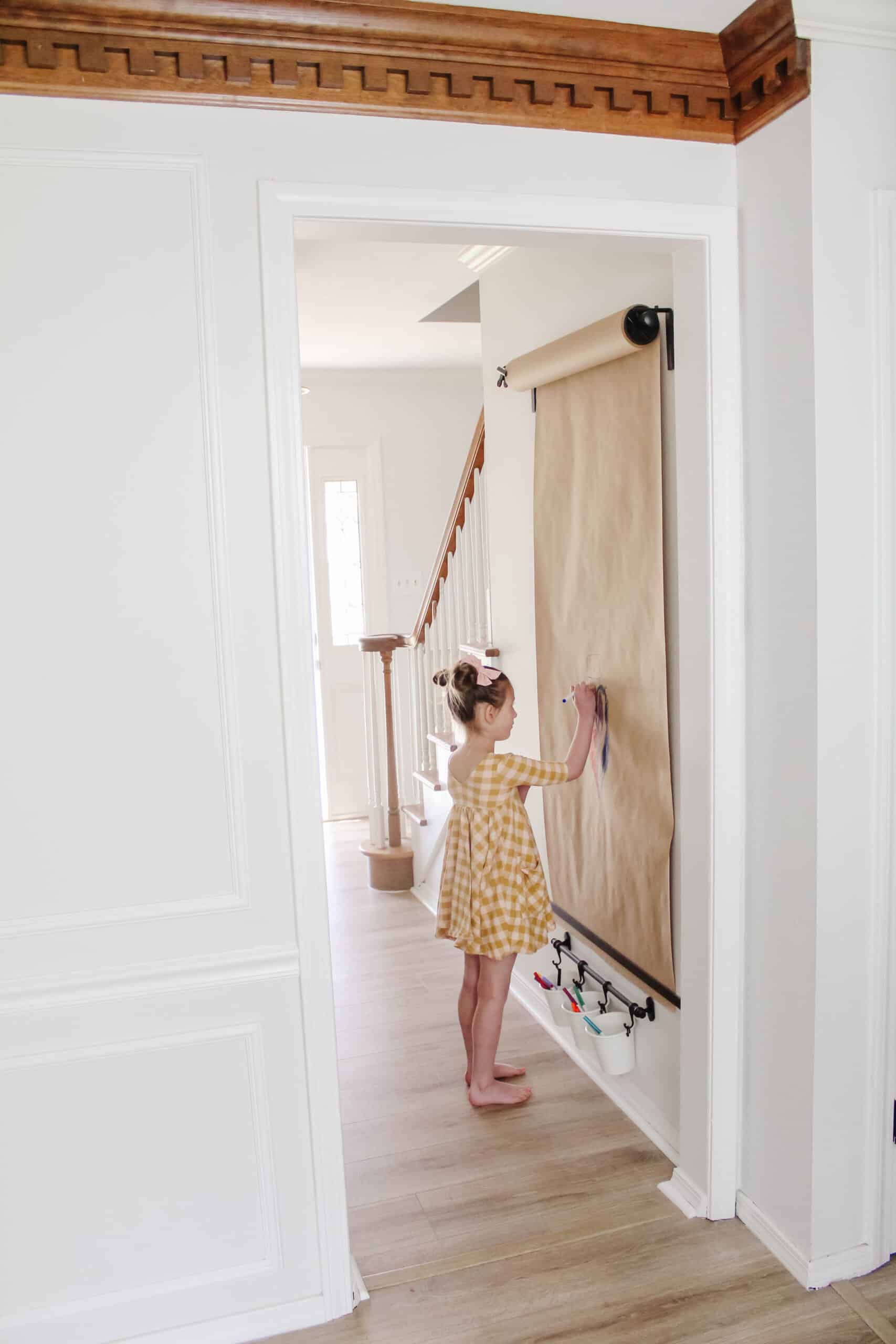 little girl coloring at wall mounted easel