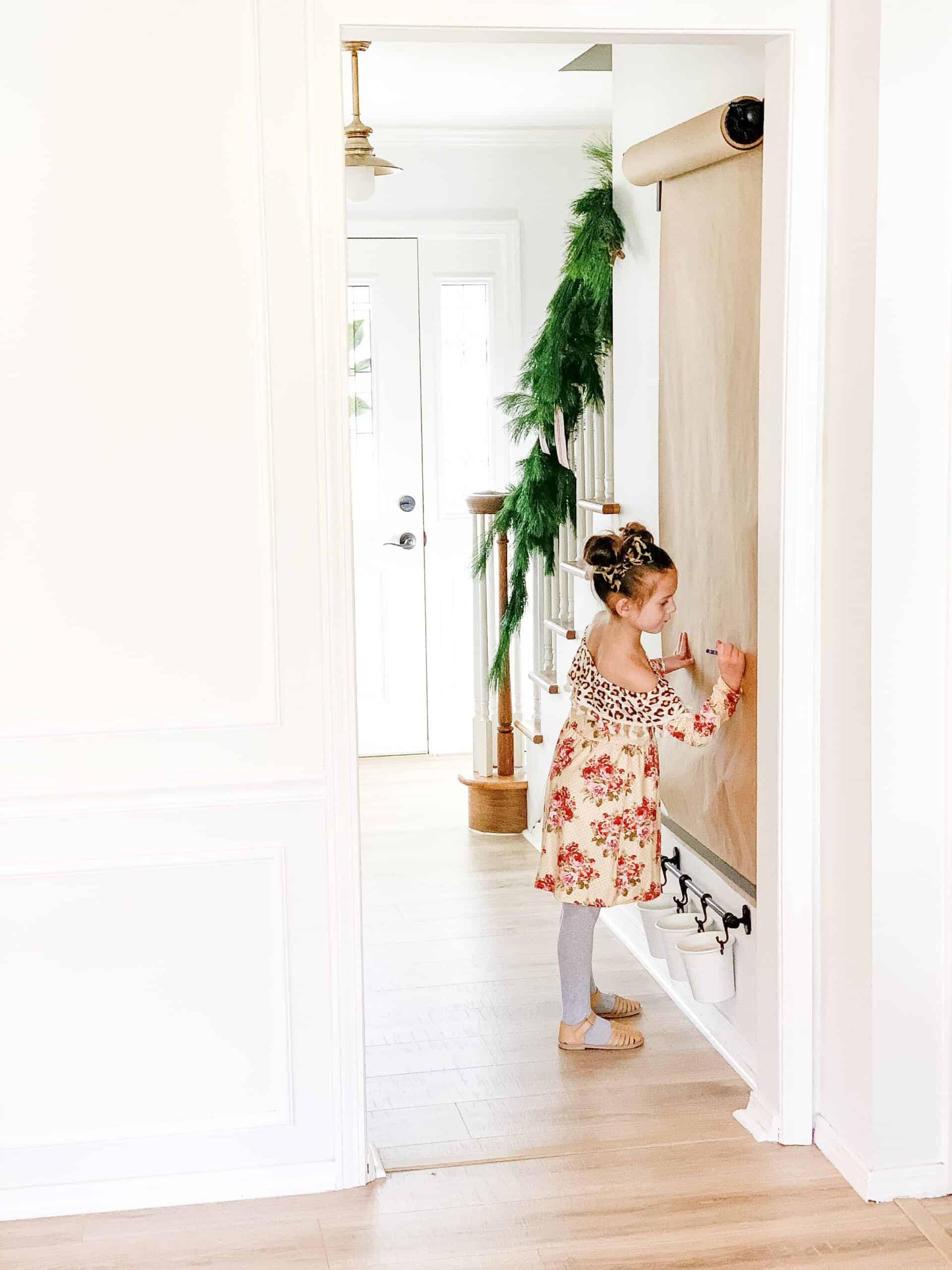 little girl coloring on wall mounted easel