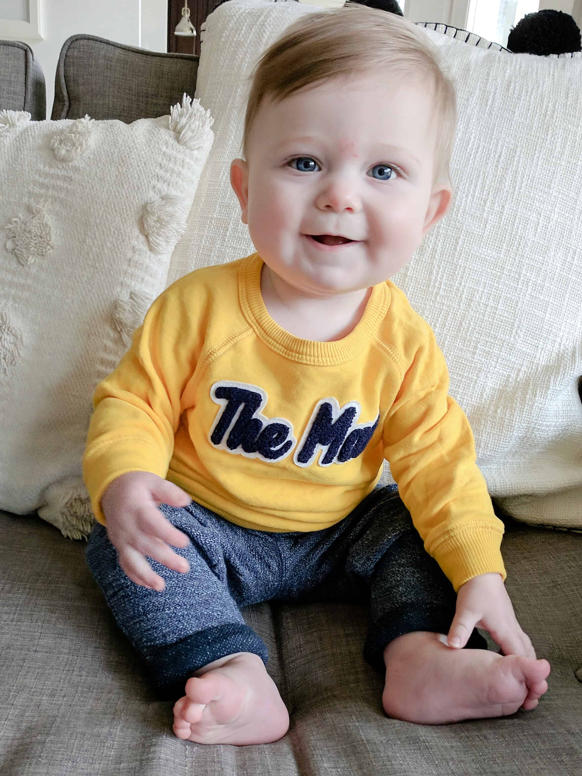baby boy in yellow sweatshirt on couch