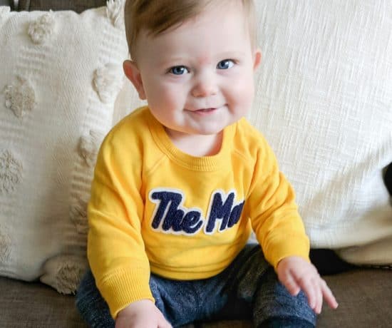 baby boy in yellow sweatshirt on couch
