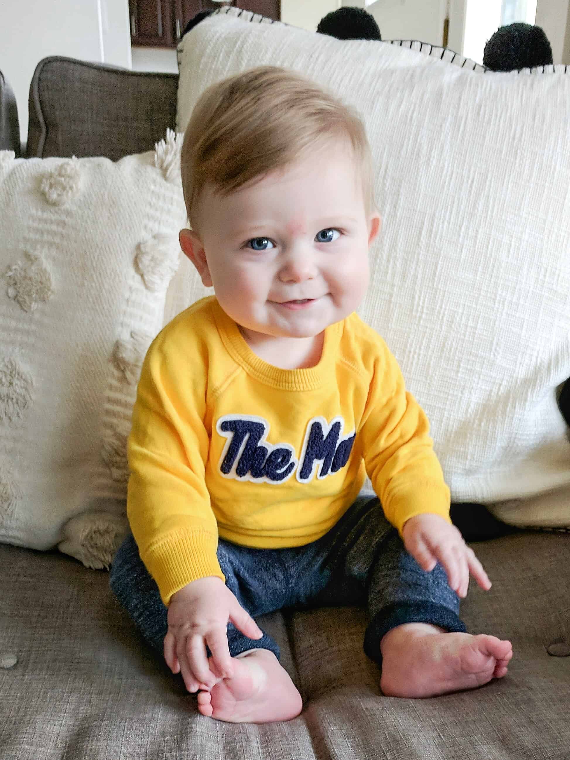 baby boy in yellow sweatshirt on couch