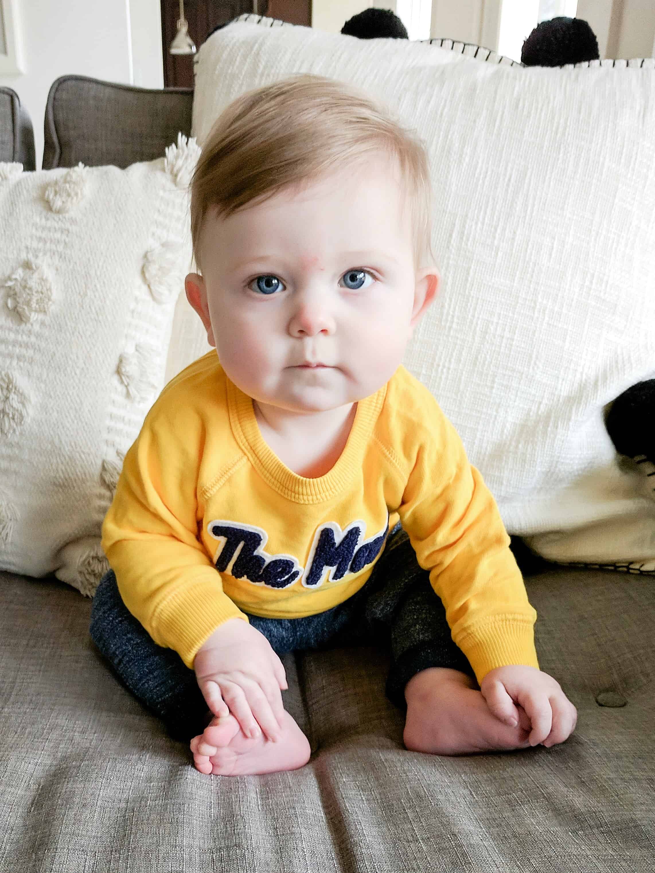 baby boy in yellow sweatshirt on couch