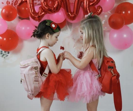 two toddlers in front of pink and red balloons with fawn design mini bags