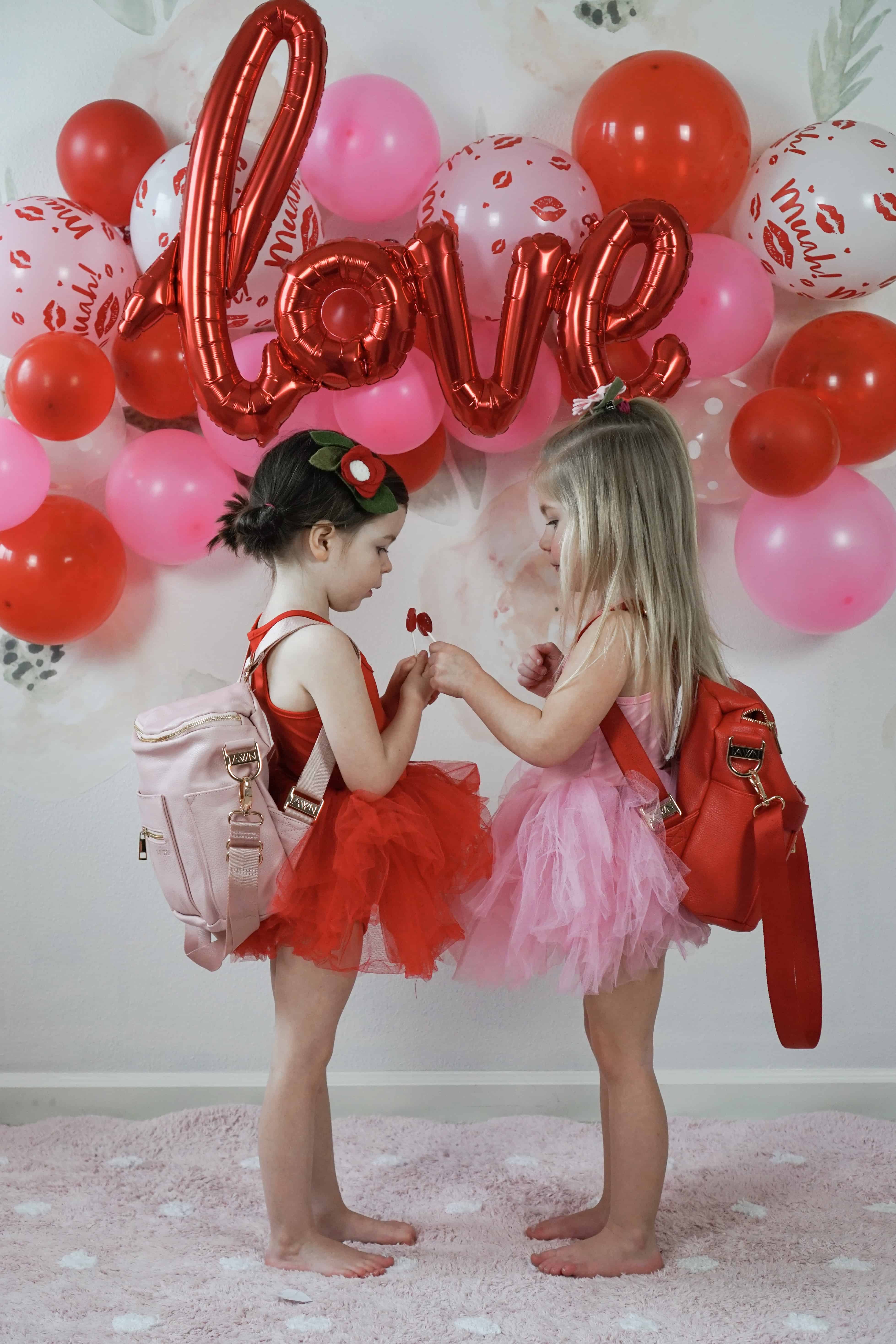 two toddlers in front of pink and red balloons with fawn design mini bags