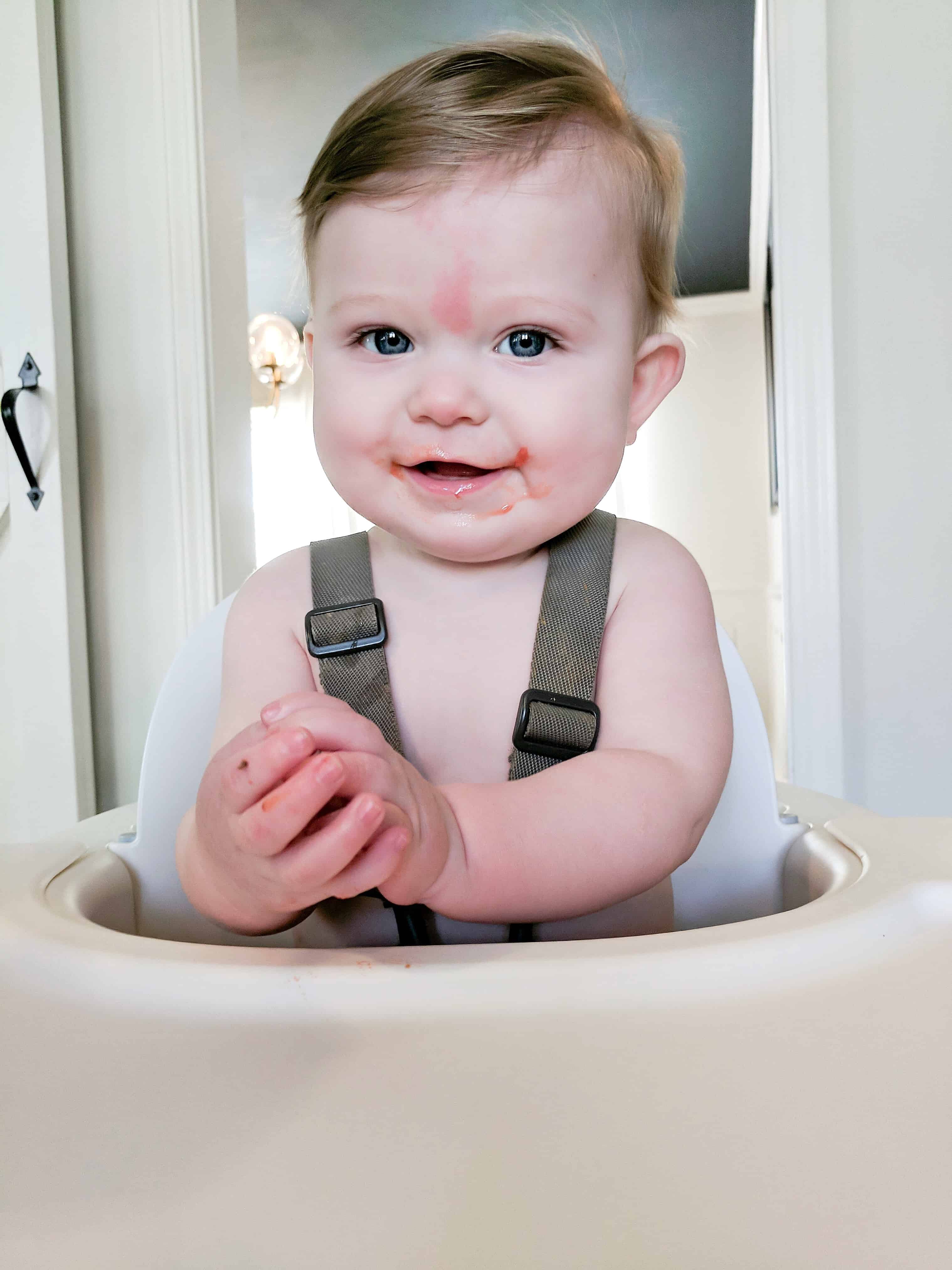 Baby in highchair with food on his face