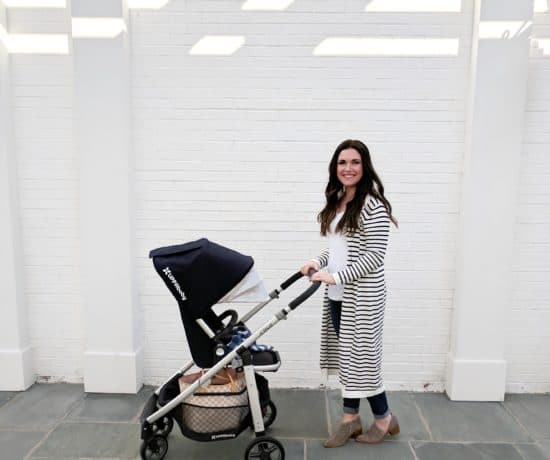mom pushing stroller by white wall