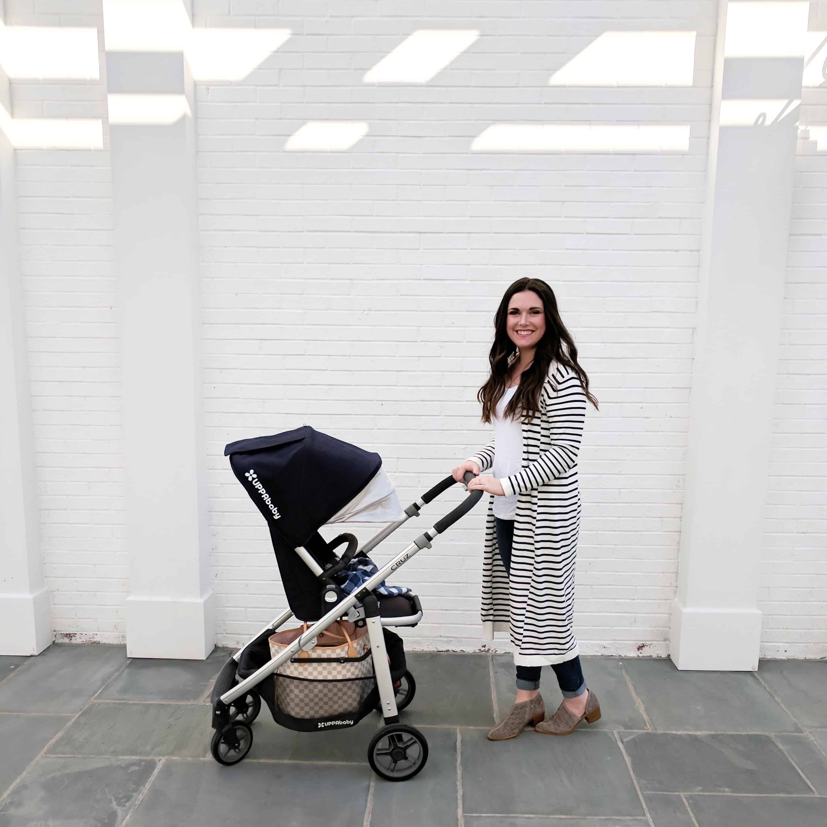 mom pushing stroller by white wall | Buying a Stroller 