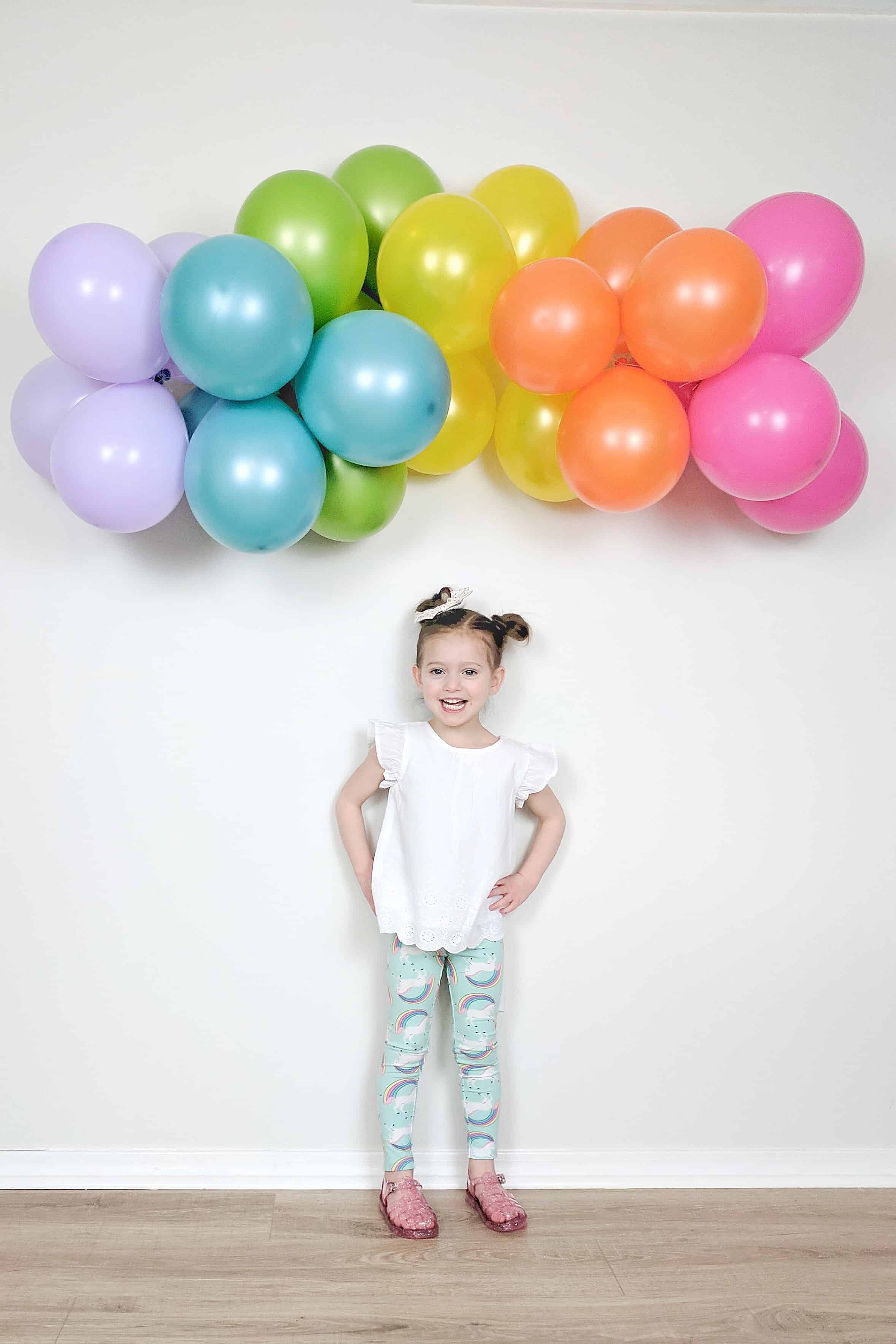 little girl under balloon rainbow