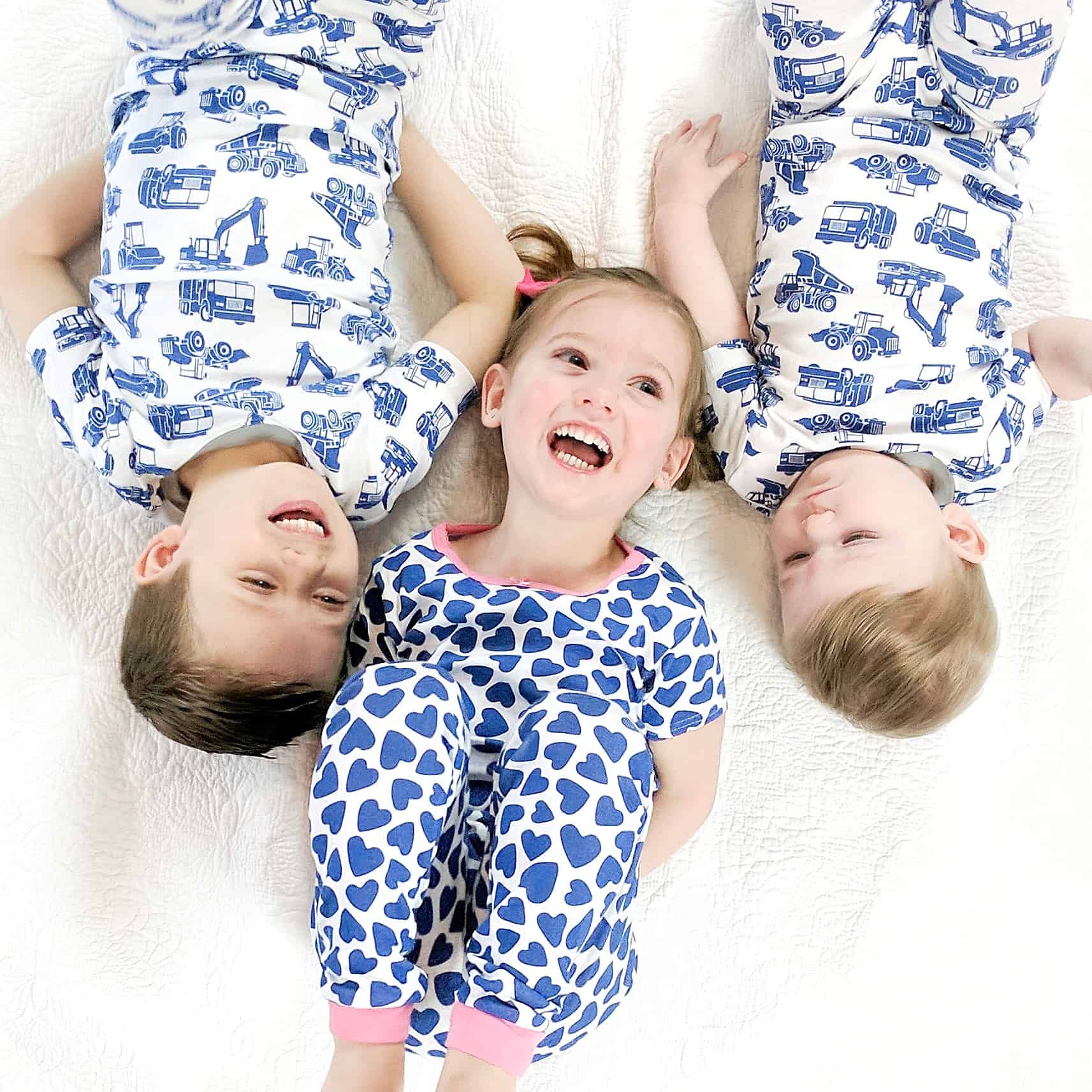 three kids laying on bed in matching pajamas