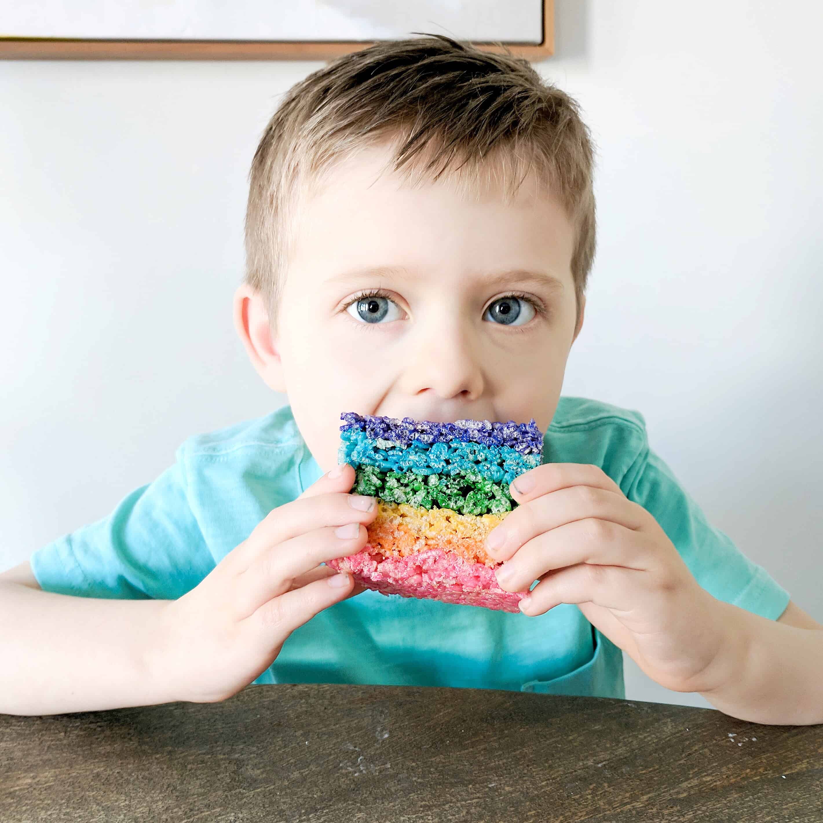 boy in green shirt eating rainbow rice Krispy treat