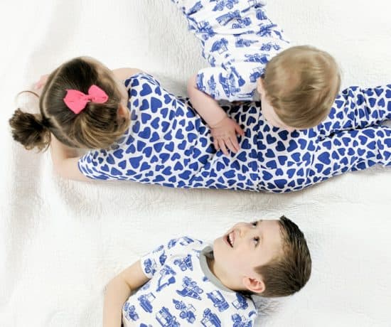 three kids laying on bed in matching pajamas
