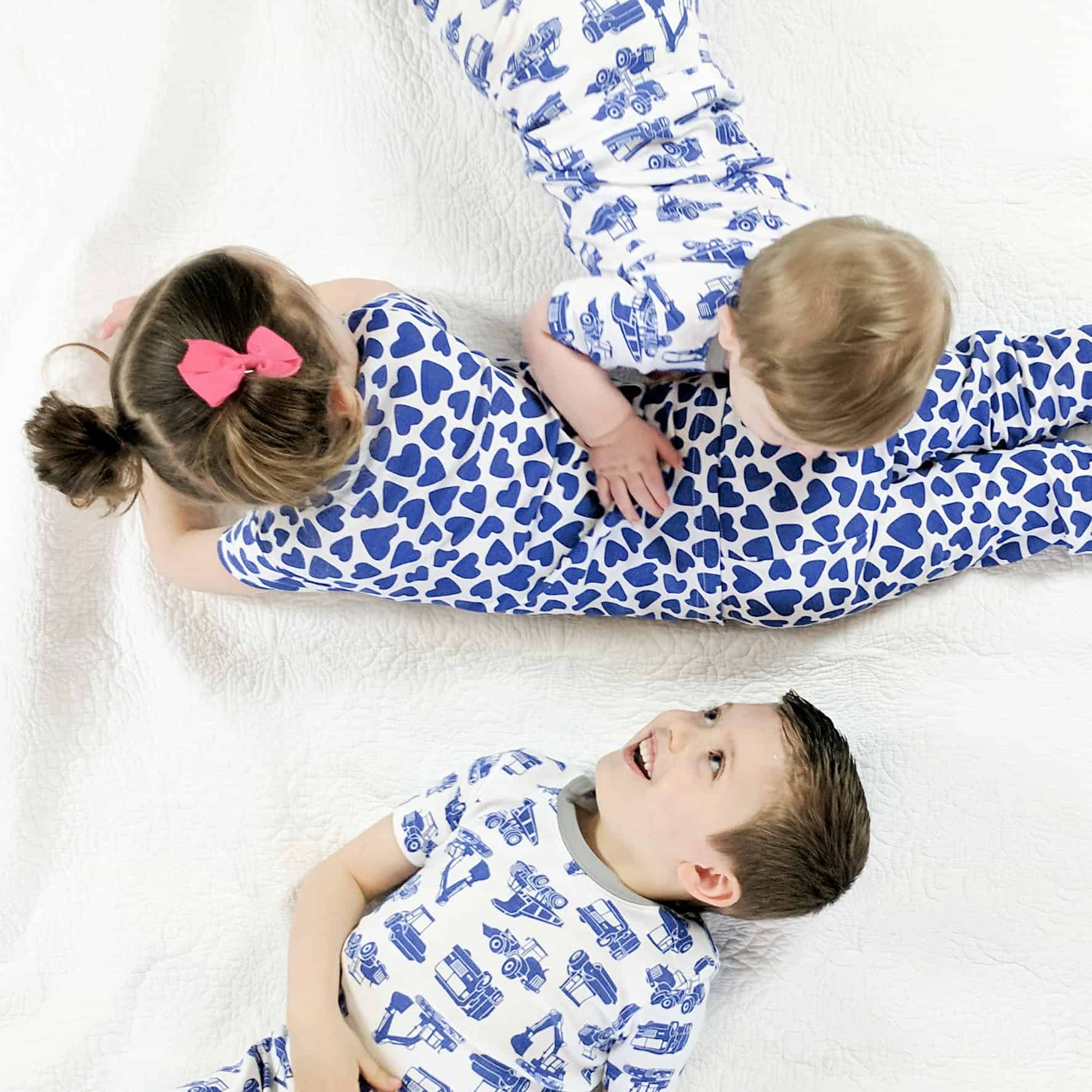 three kids laying on bed in matching pajamas
