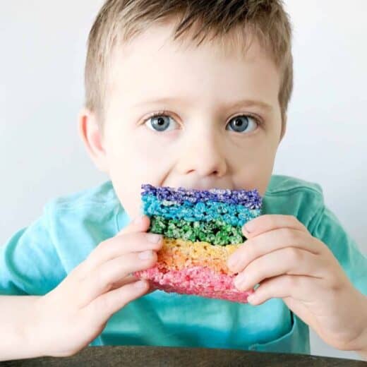 boy in green shirt eating rainbow rice Krispy treat