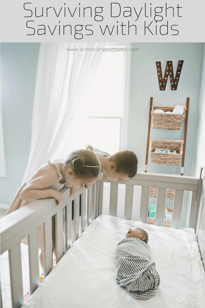 two toddlers looking at baby in a crib