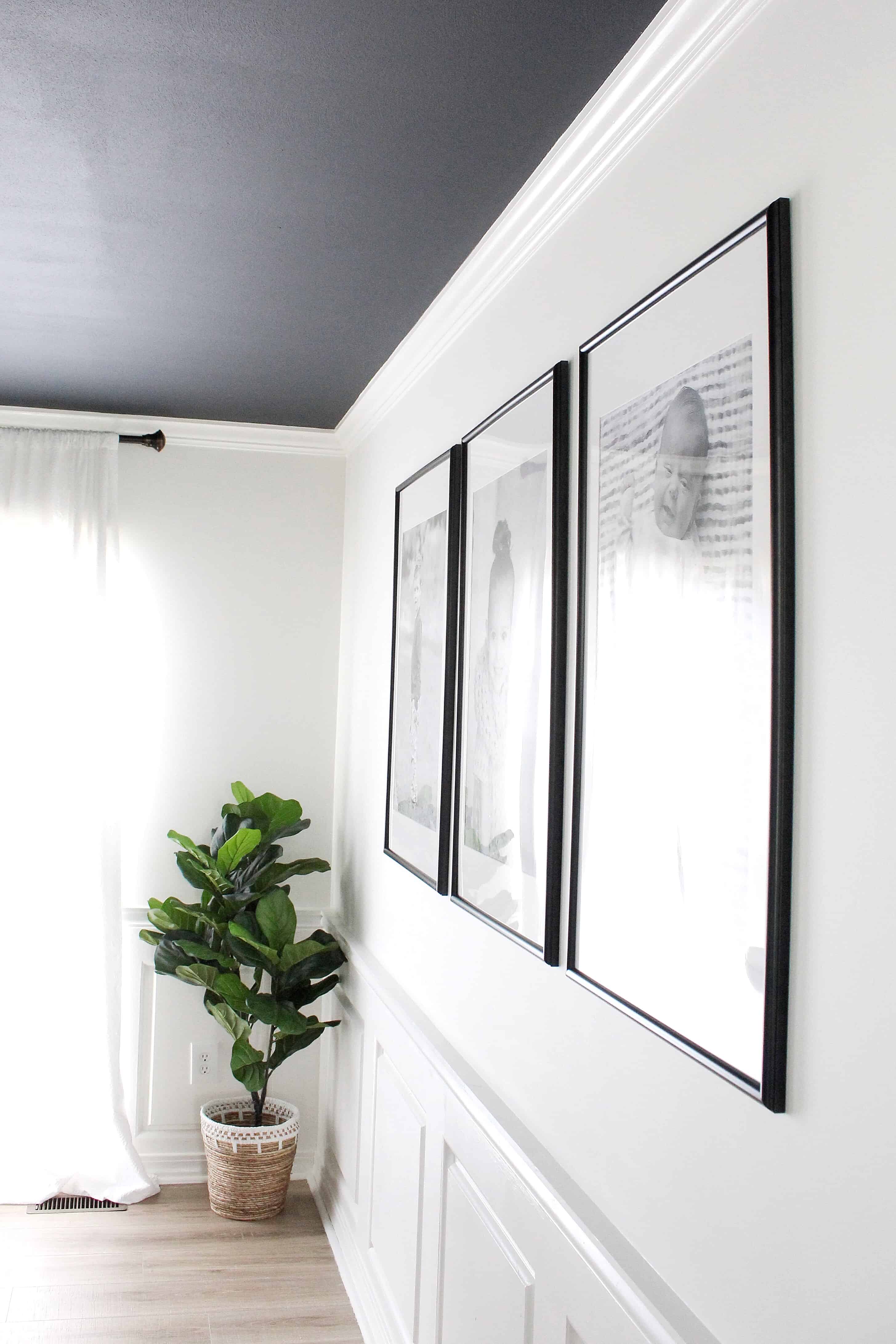 White wall with three large black frames and engineering prints | Modern Dining Room with Dark Ceiling