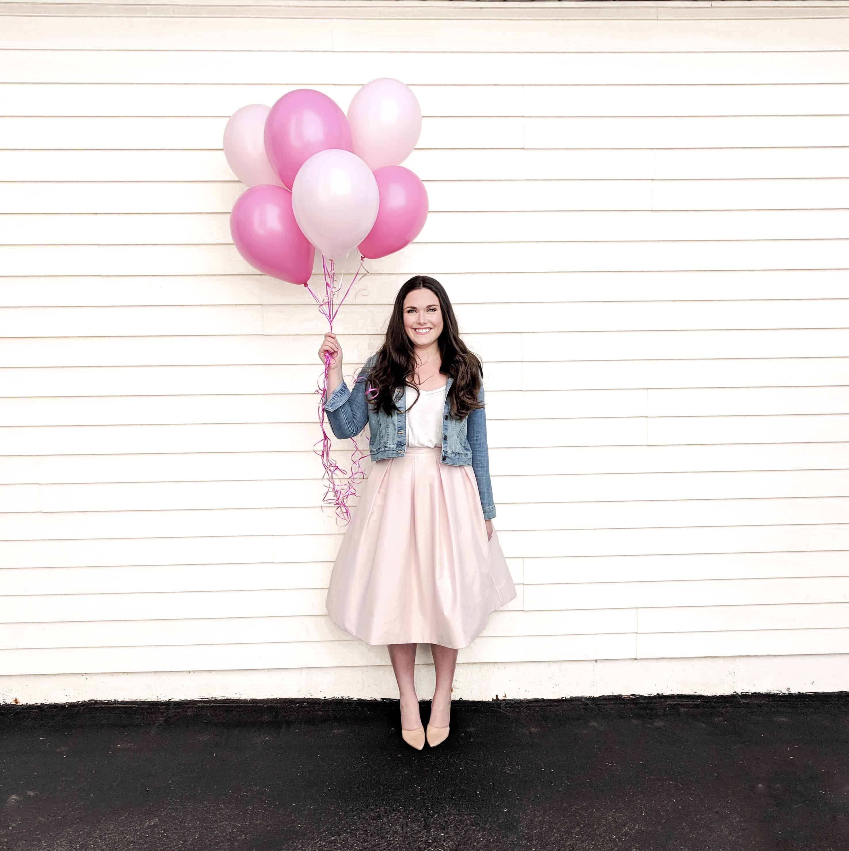 woman in pink skirt holding pink balloons