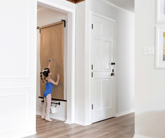 little girl standing by dutch door and wall mounted easel