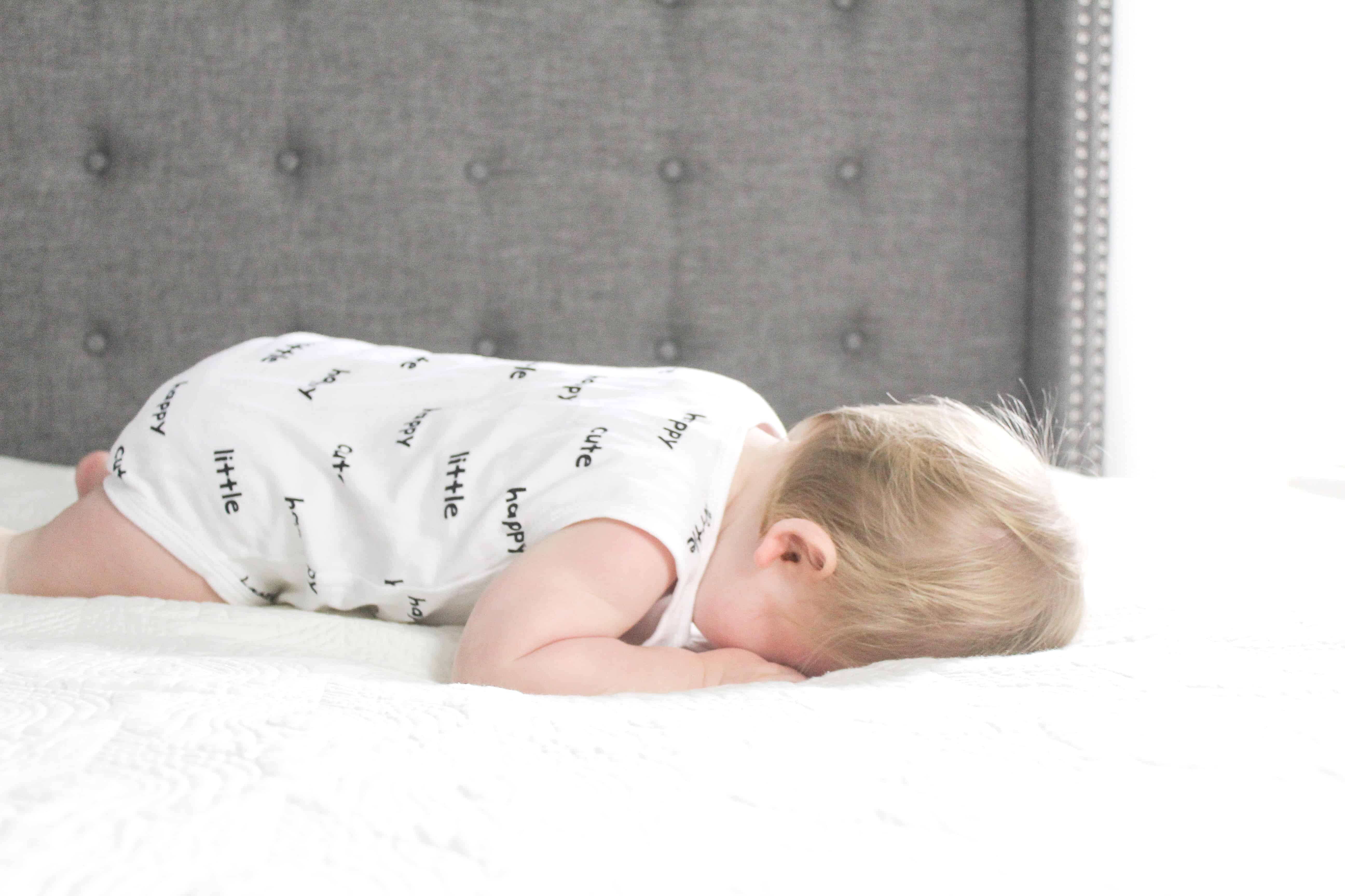 baby laying on bed in carters onsie