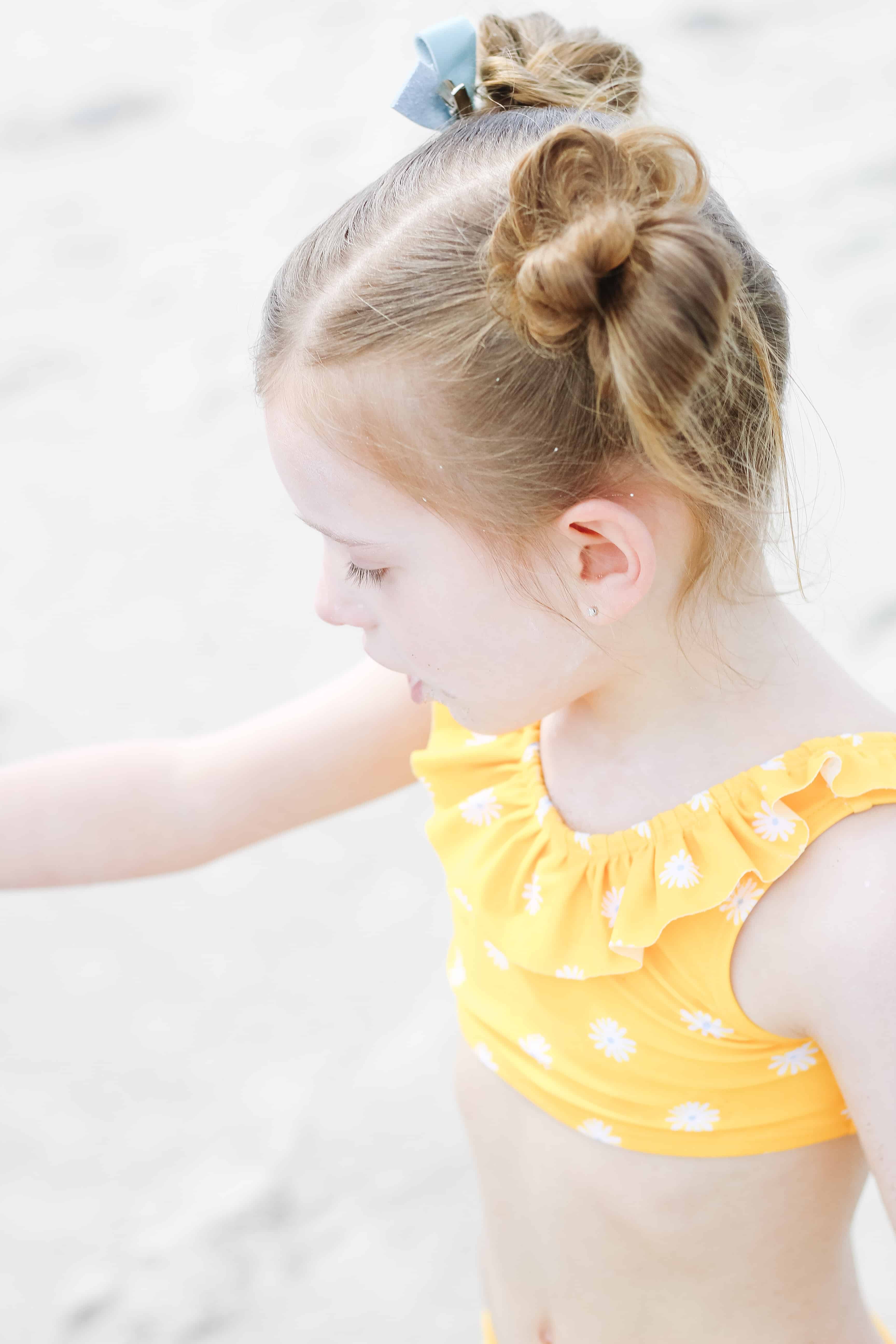 little girl in yellow swimsuit playing on beach