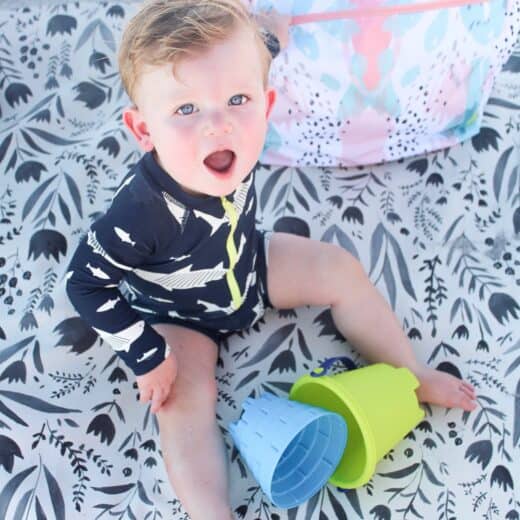 baby boy on the beach on gathre mat with Logan and lenora bag