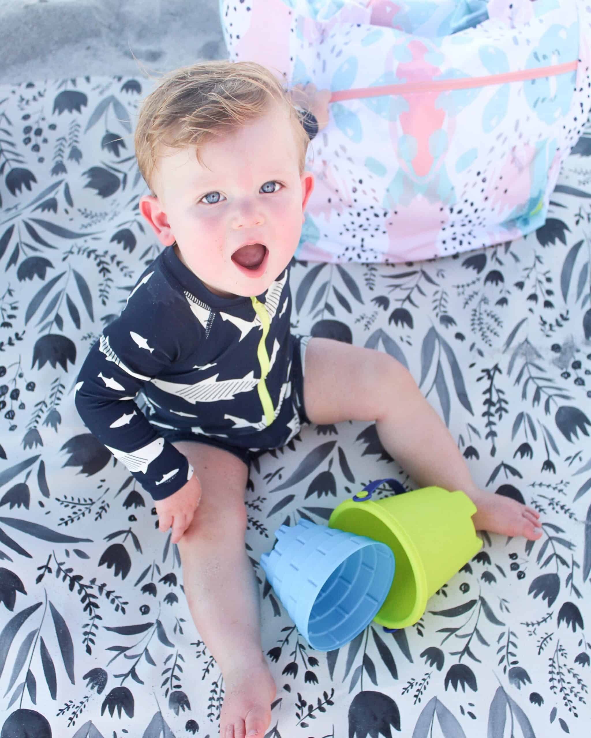 baby boy on the beach on gathre mat with Logan and lenora bag