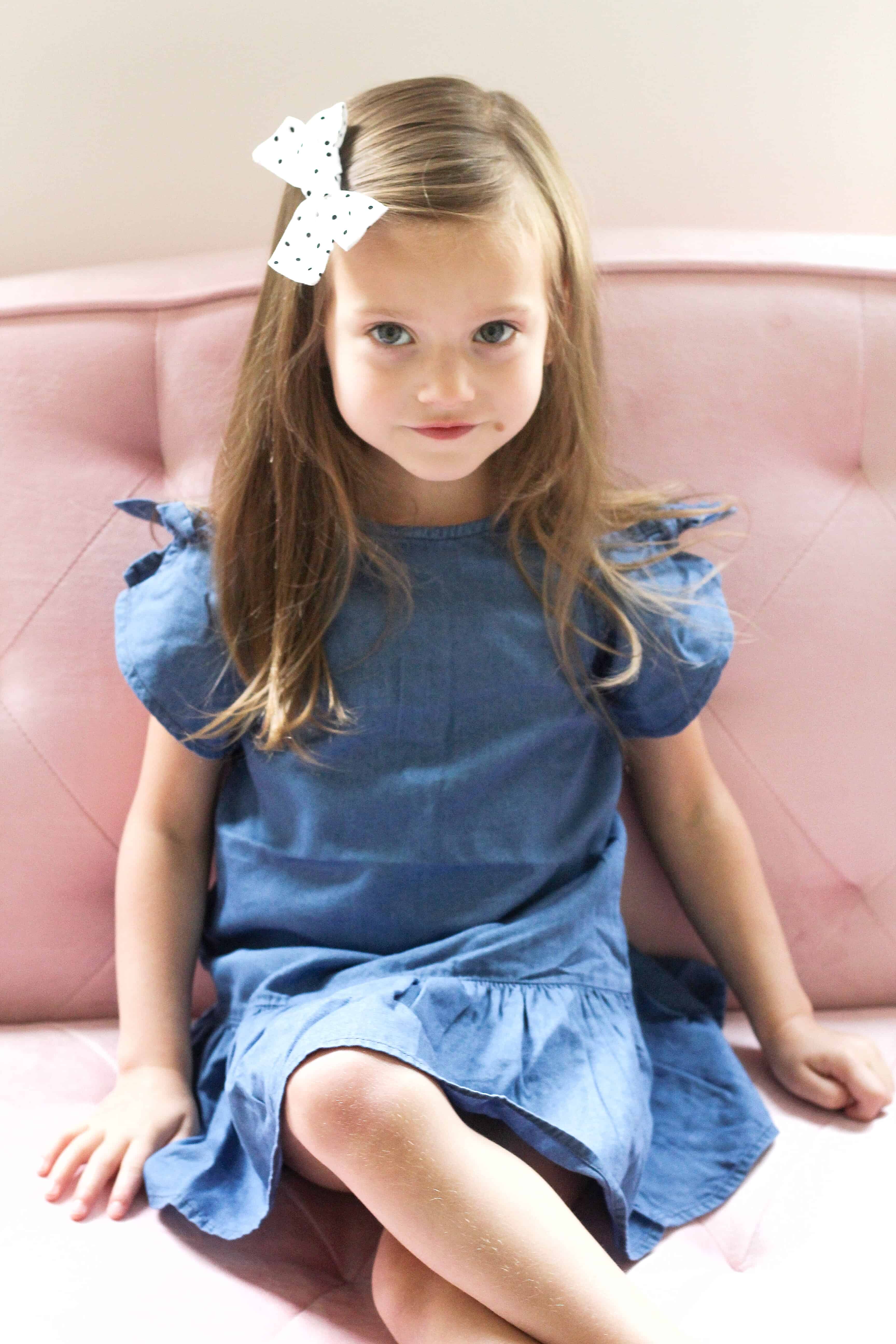 little girl on pink couch in Carter's Dress