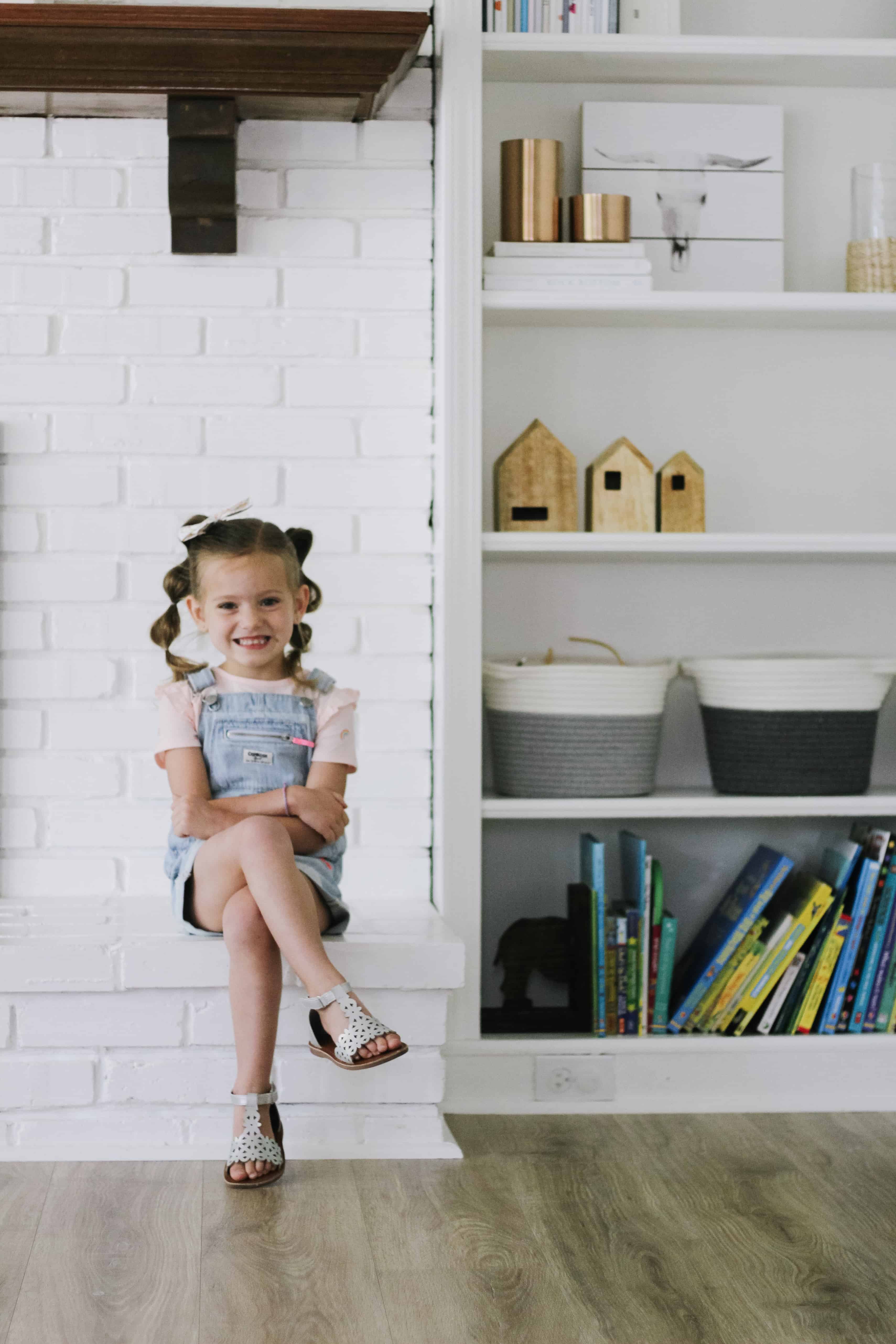 toddler girl sitting on white fireplace