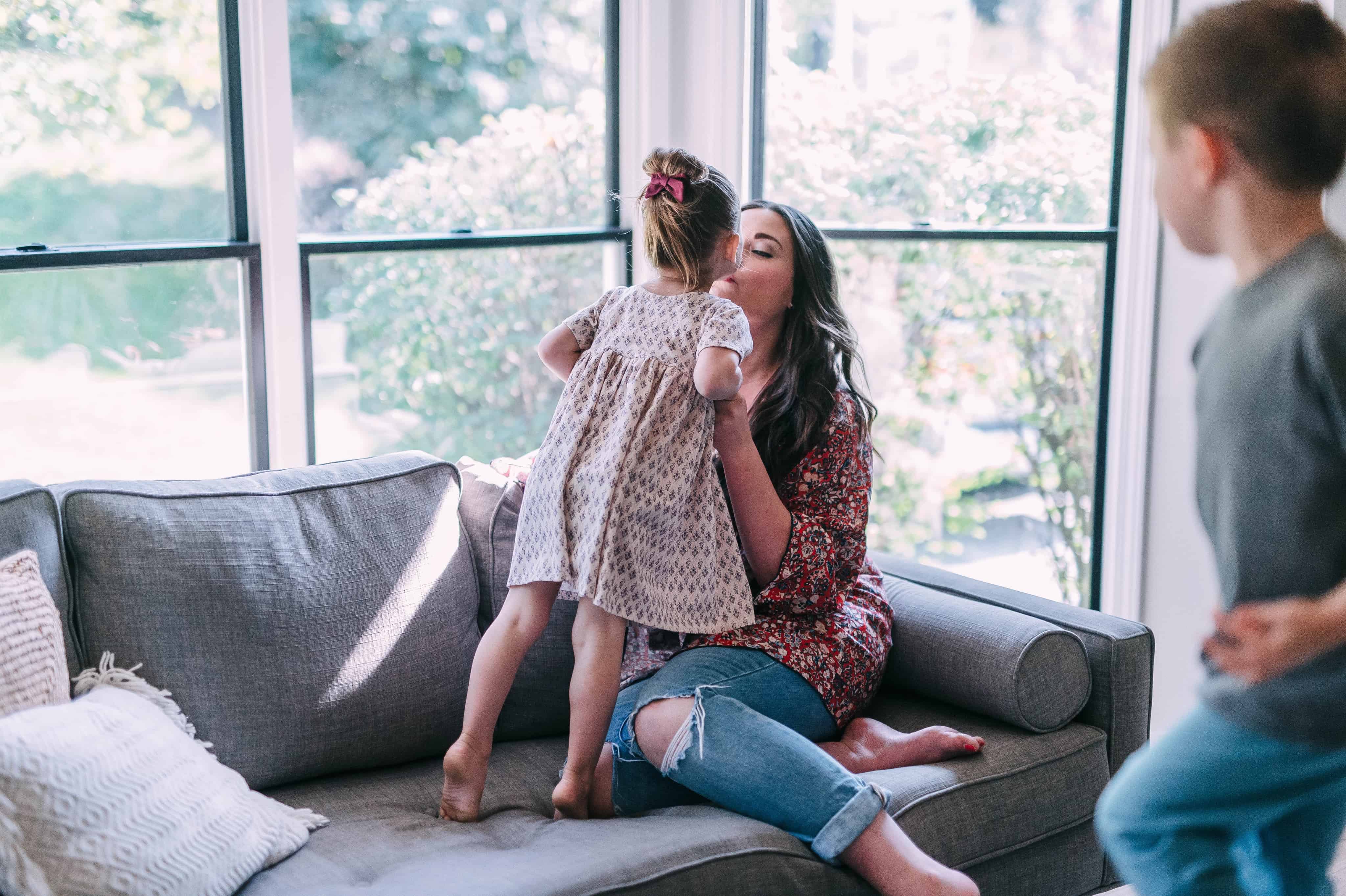 toddler girl kissing mom on couch