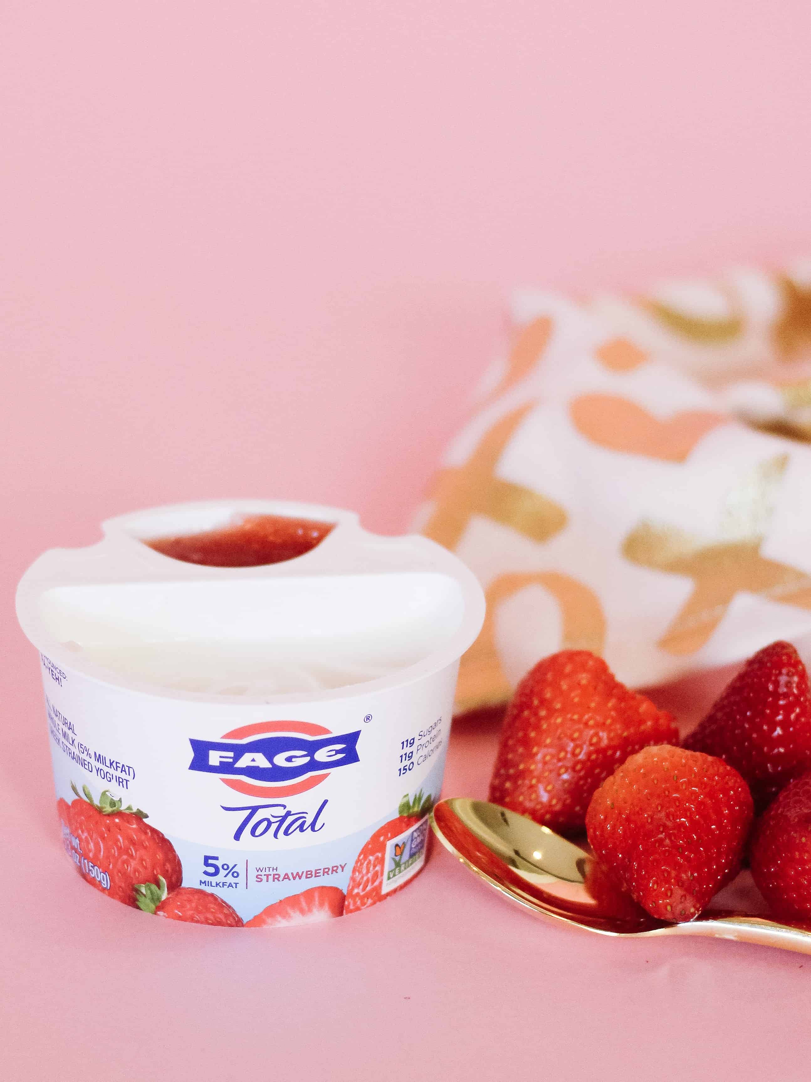 FAGE Total Split cup yogurt against pink background with gold spoon and strawberries
