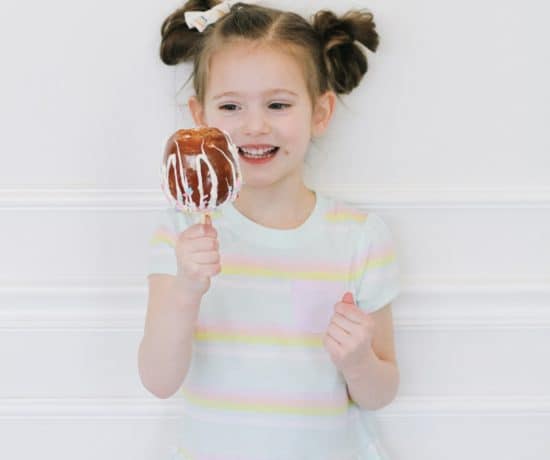 Little girl eating a unicorn caramel apple