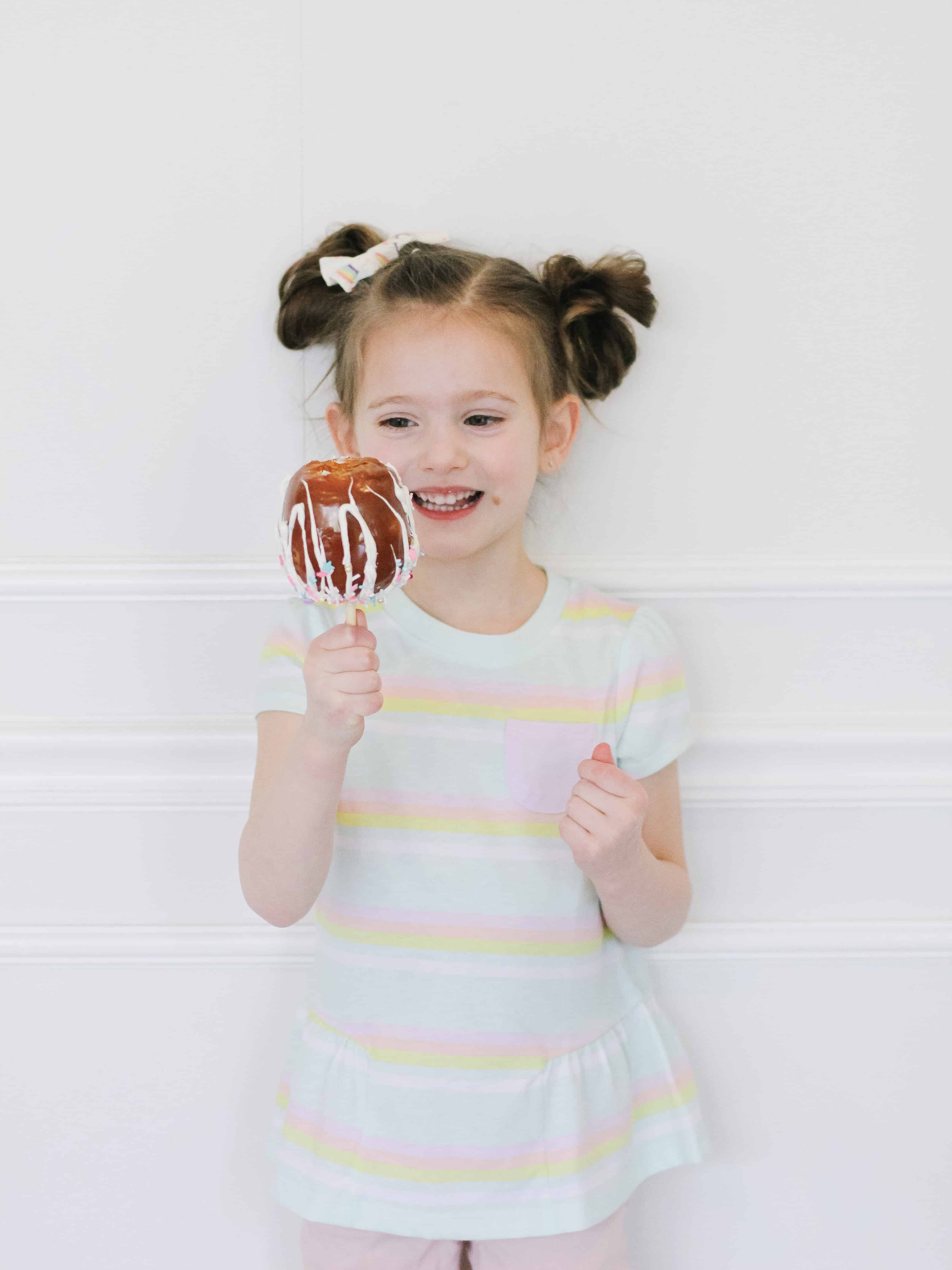 Little girl eating a unicorn caramel apple