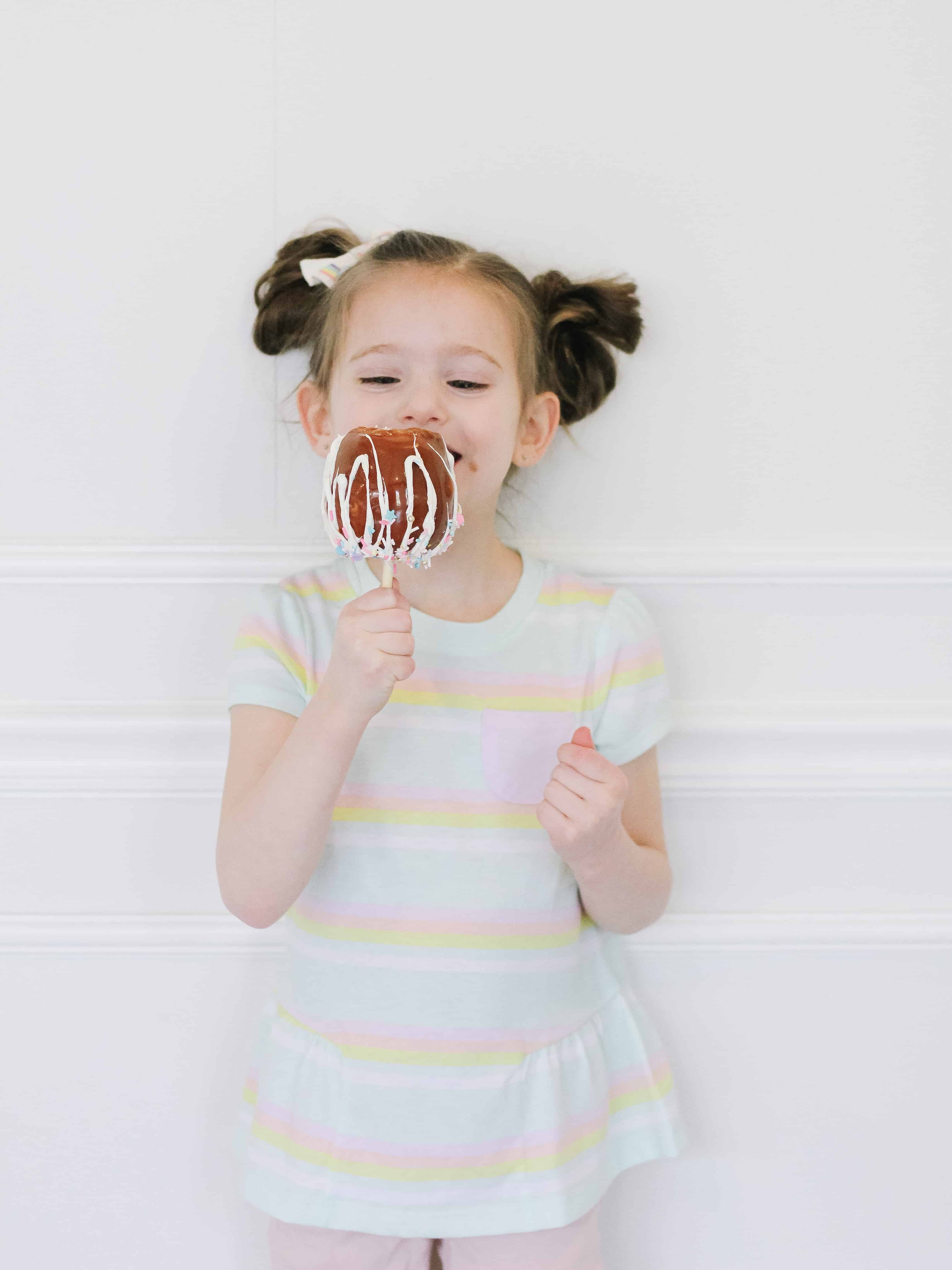 Little girl eating caramel apple