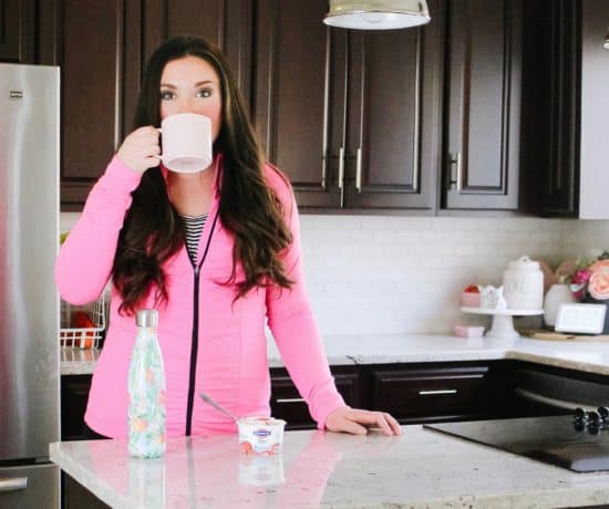 mom drinking coffee in kitchen with pink sweatshirt on