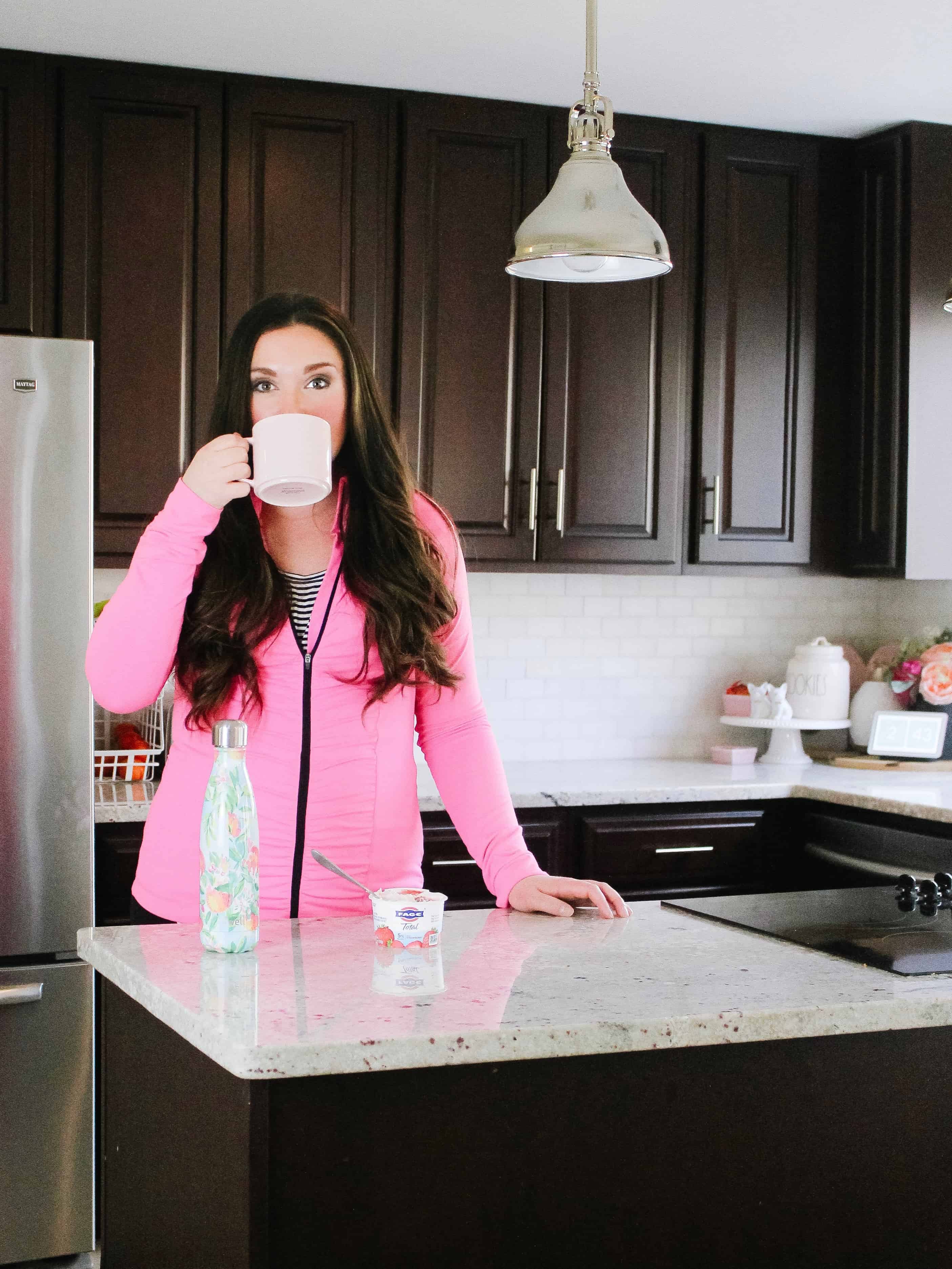 mom drinking coffee in kitchen with pink sweatshirt on