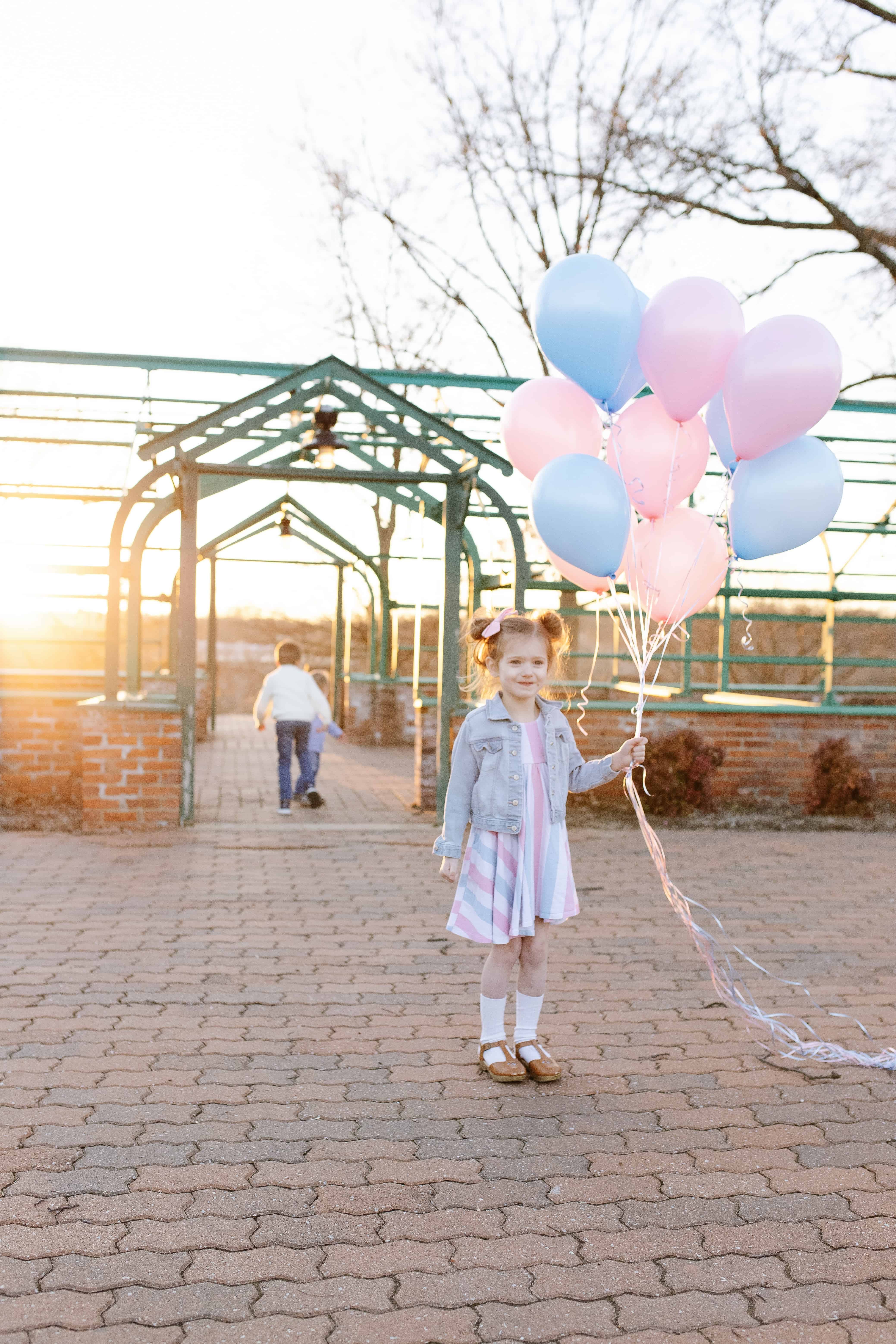 toddler girl with pink and blue balloons