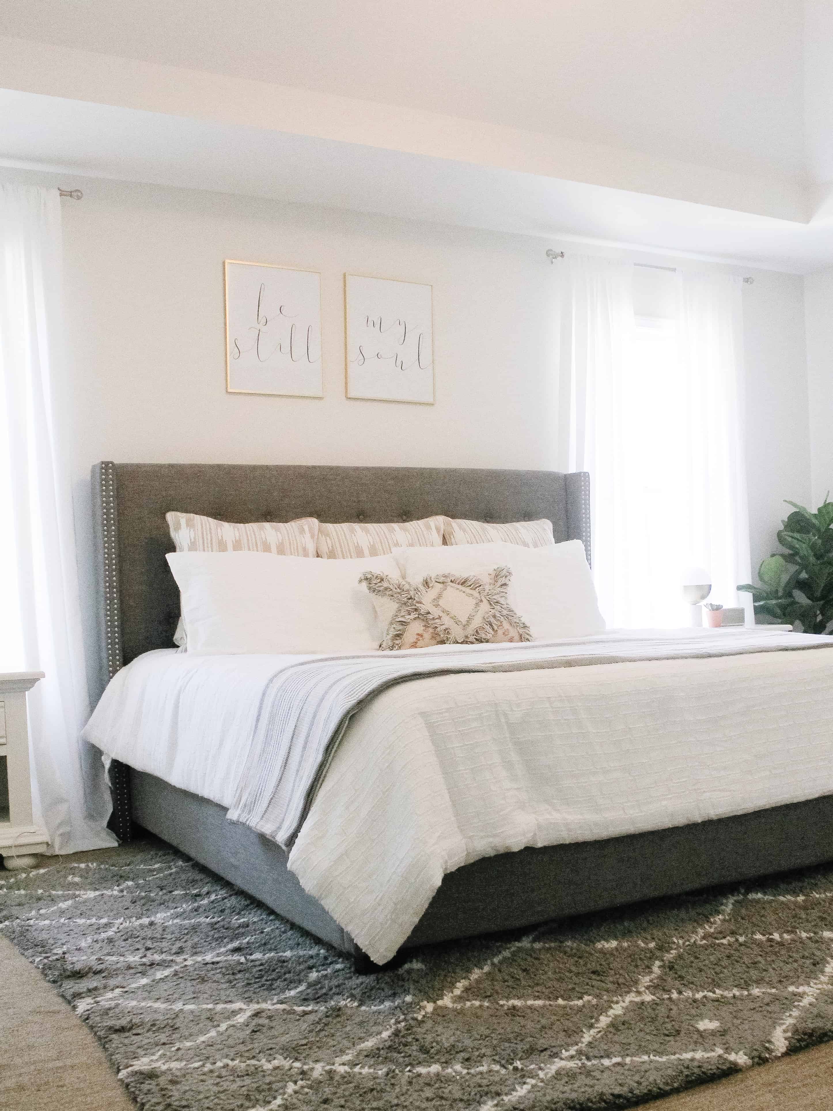 A modern neutral master bedroom with grey rug and white bedding
