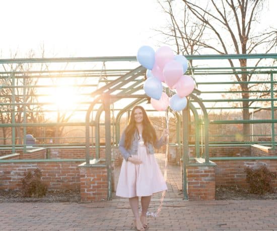 pregnant mom holding pink and blue balloons