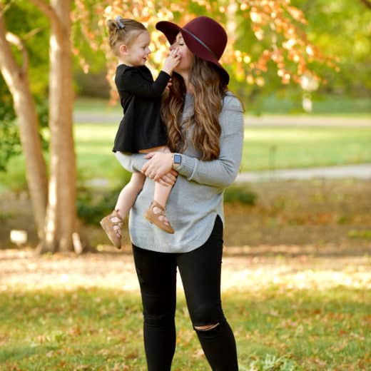mom holding toddler girl wearing maroon hat