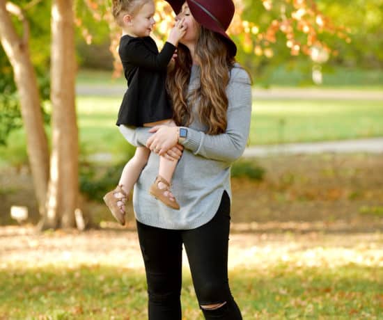 mom holding toddler girl wearing maroon hat