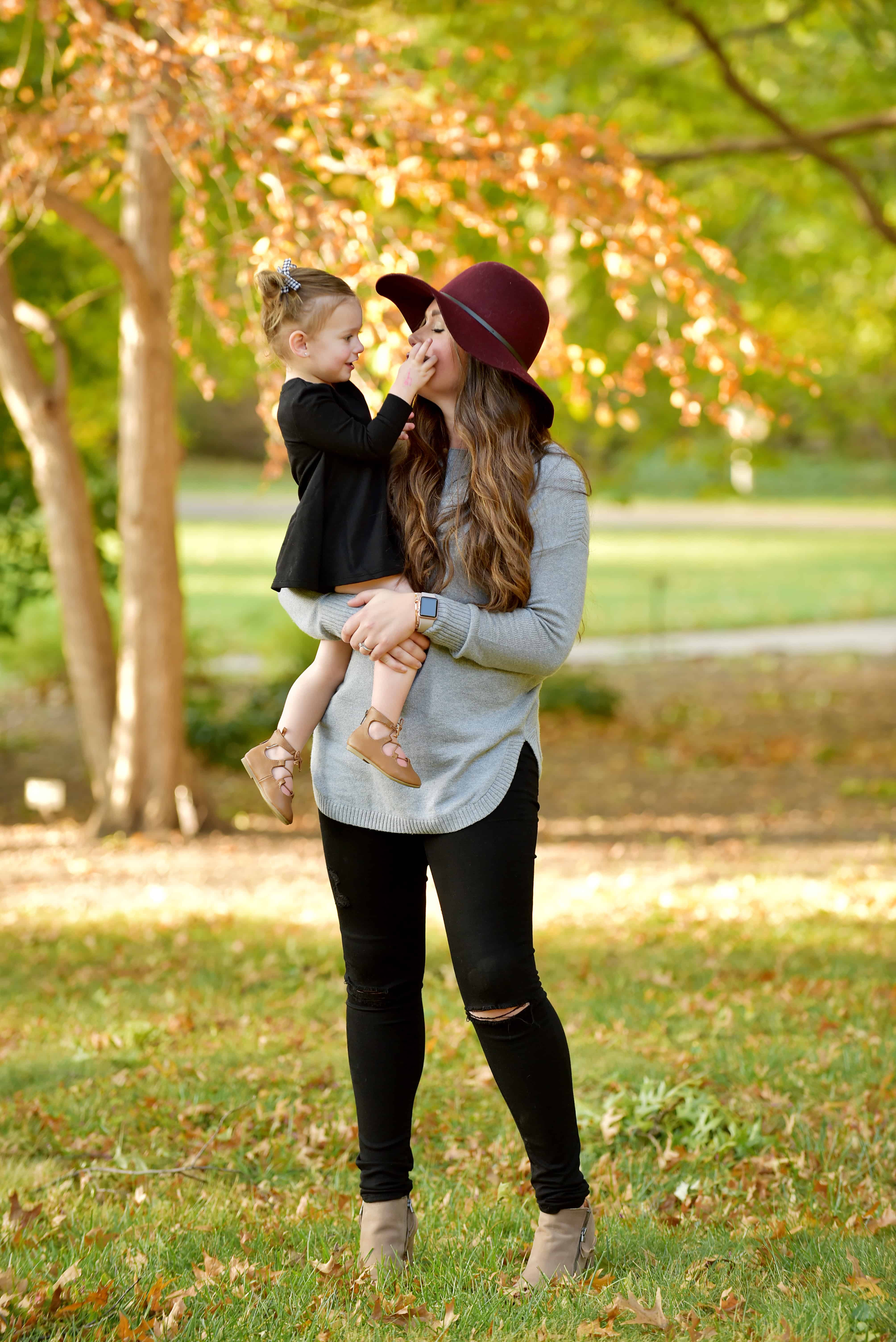 mom holding toddler girl wearing maroon hat