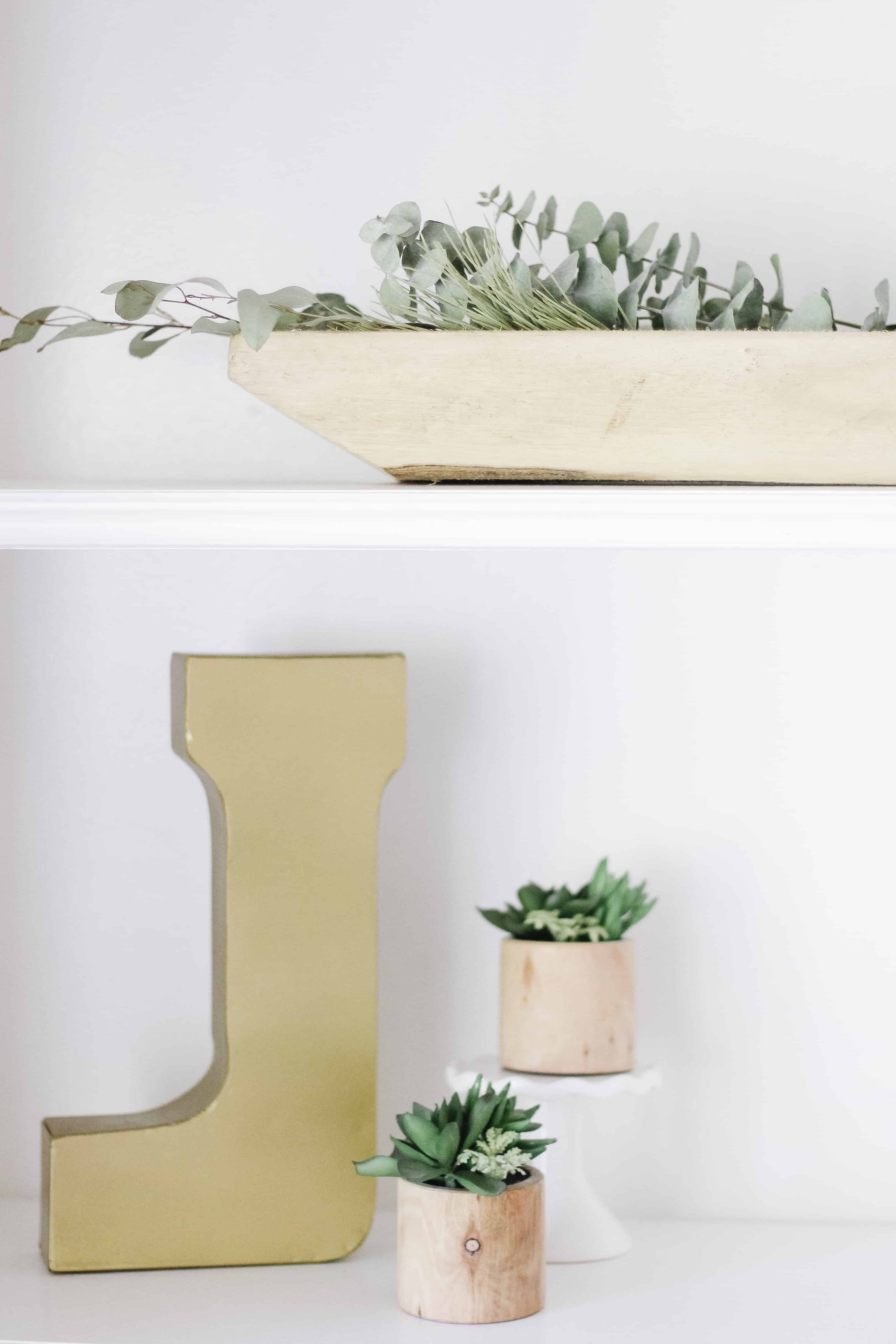 builtin shelving with gold J and wooden and greenery accents