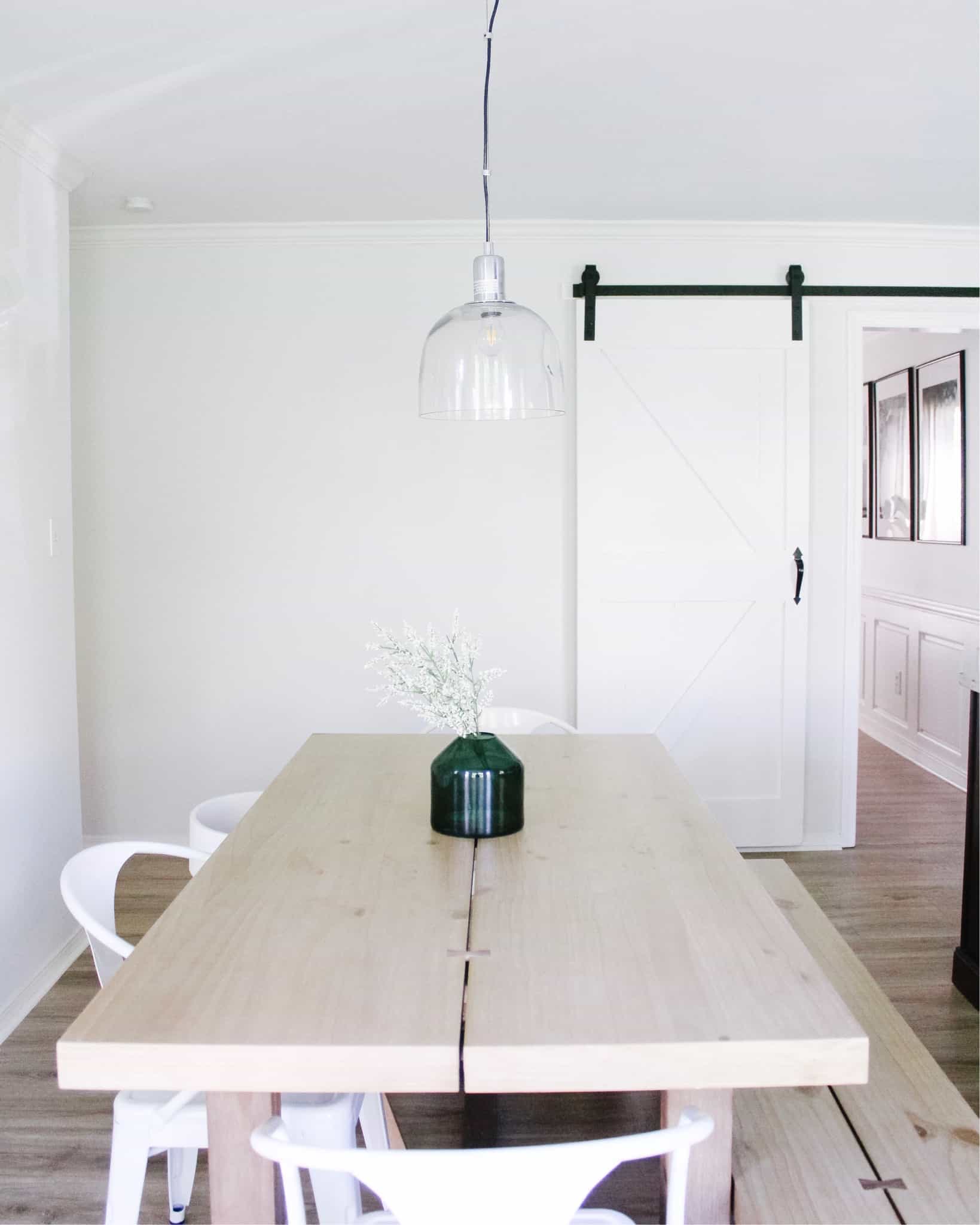 kitchen table with green vase on it and barn door