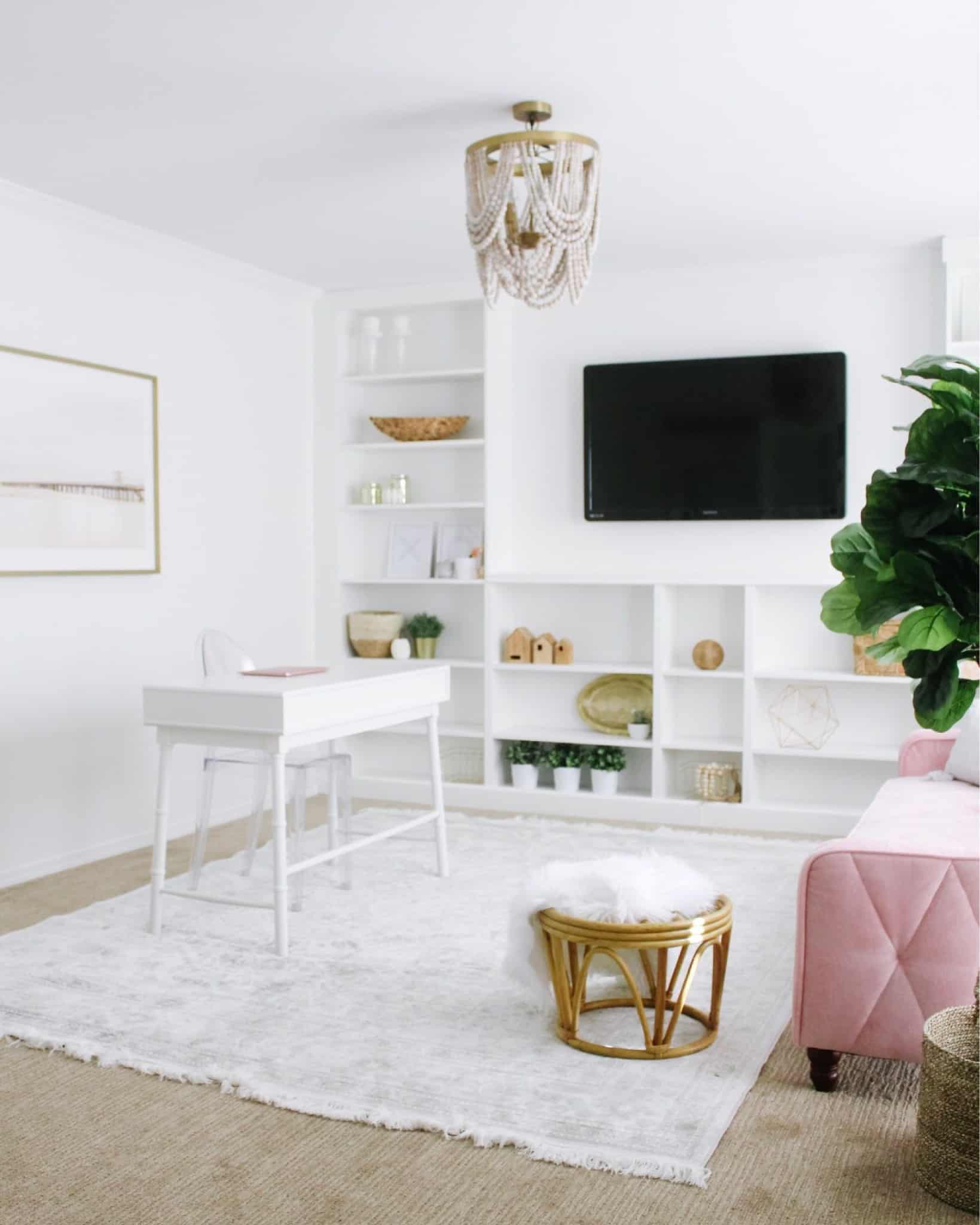modern home office with wall of built ins and pink couch