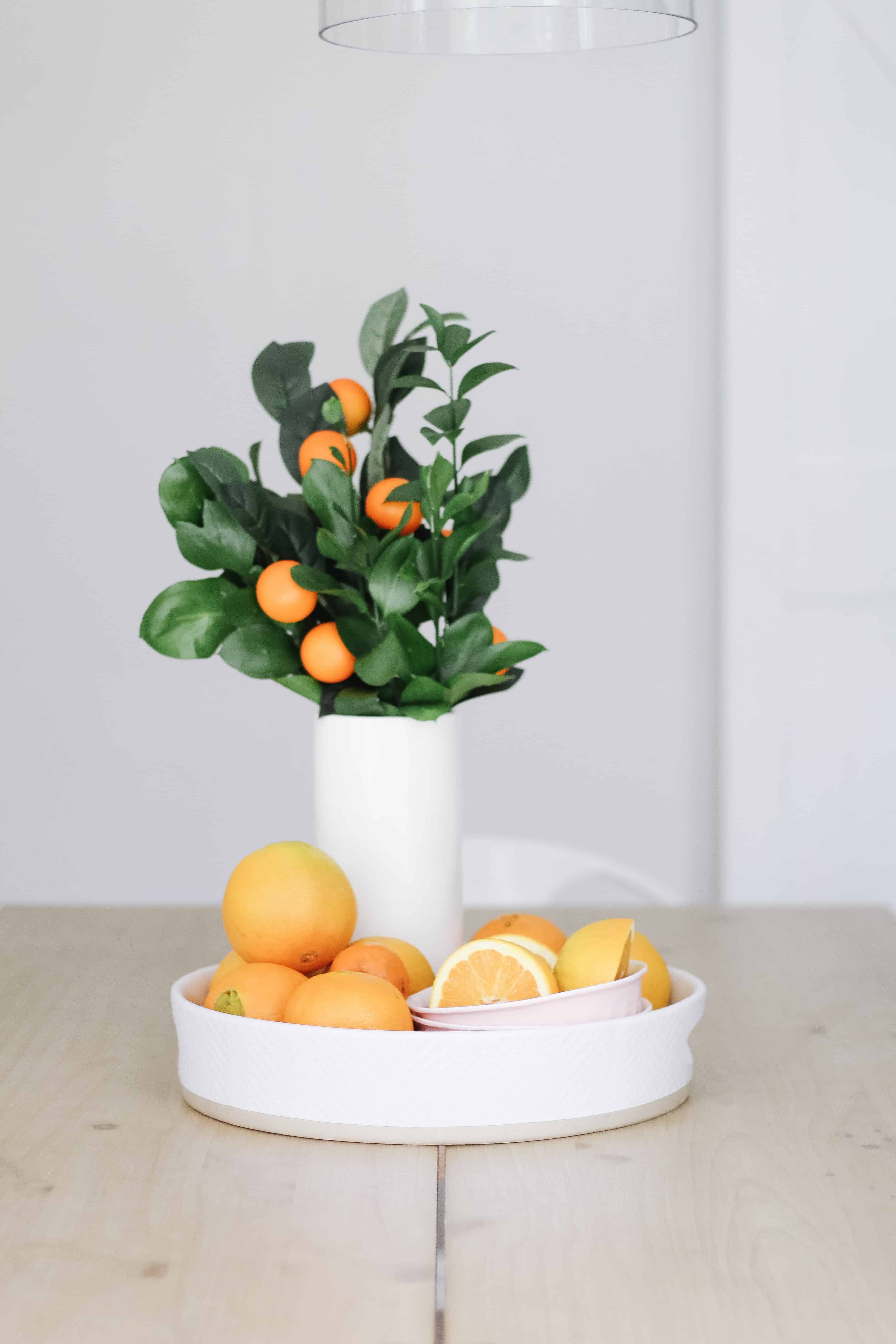 Orange centerpiece of oranges and greenery in vase