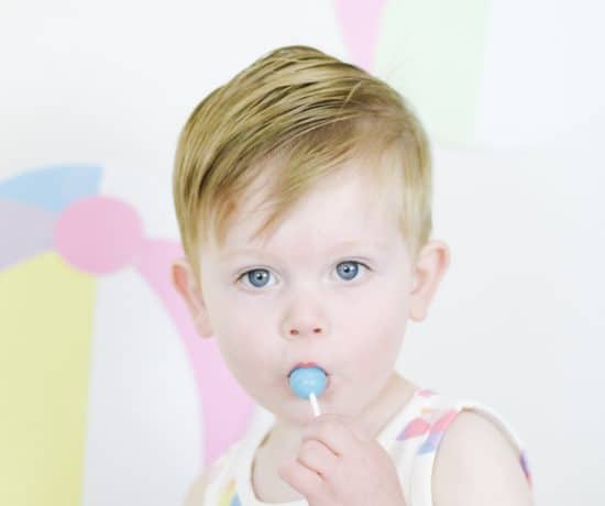 toddler boy in beach ball outfit eating sucker