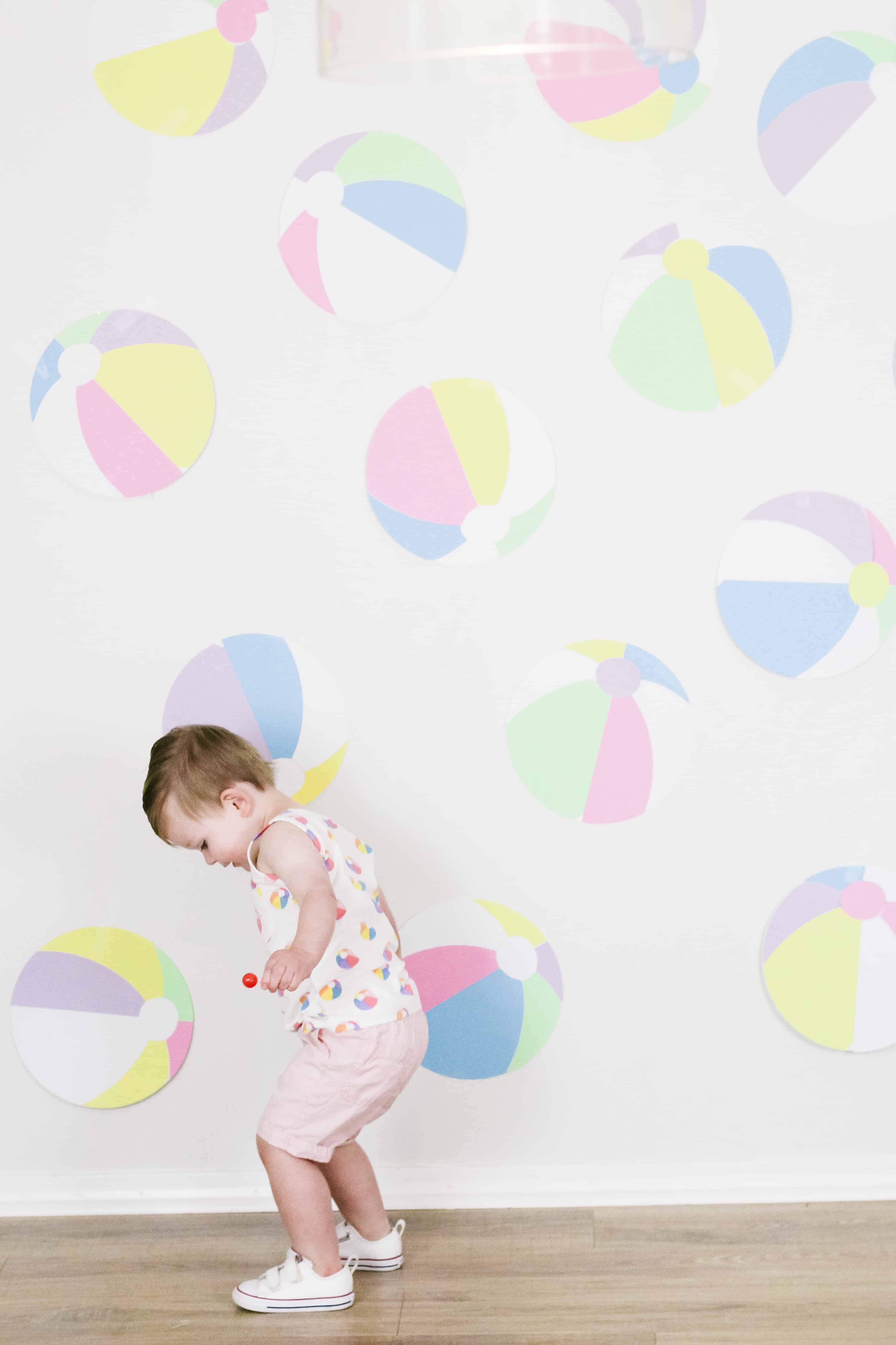 Toddler boy in beach ball themed outfit in front of beach ball wall