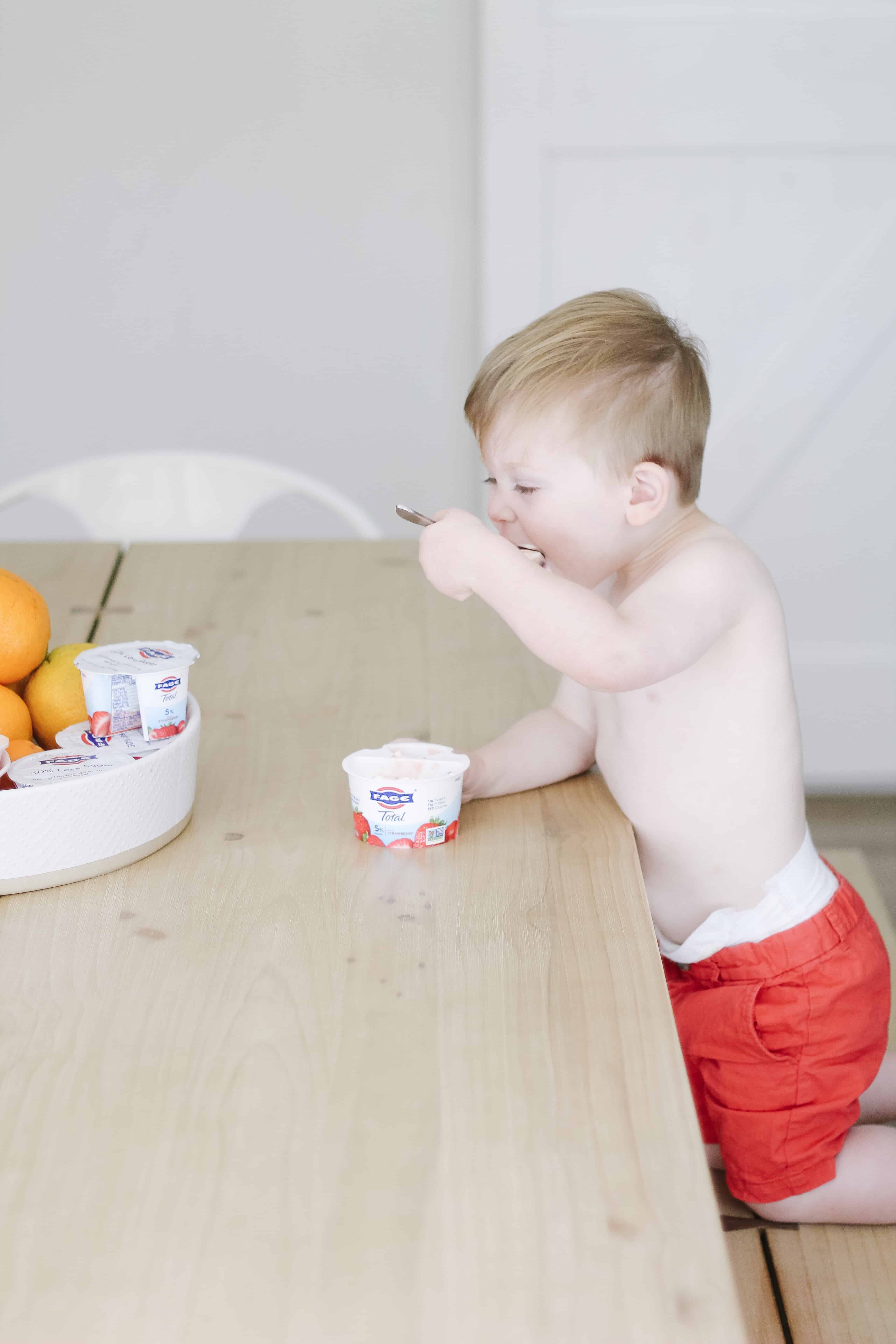 toddler boy at the table eating yogurt