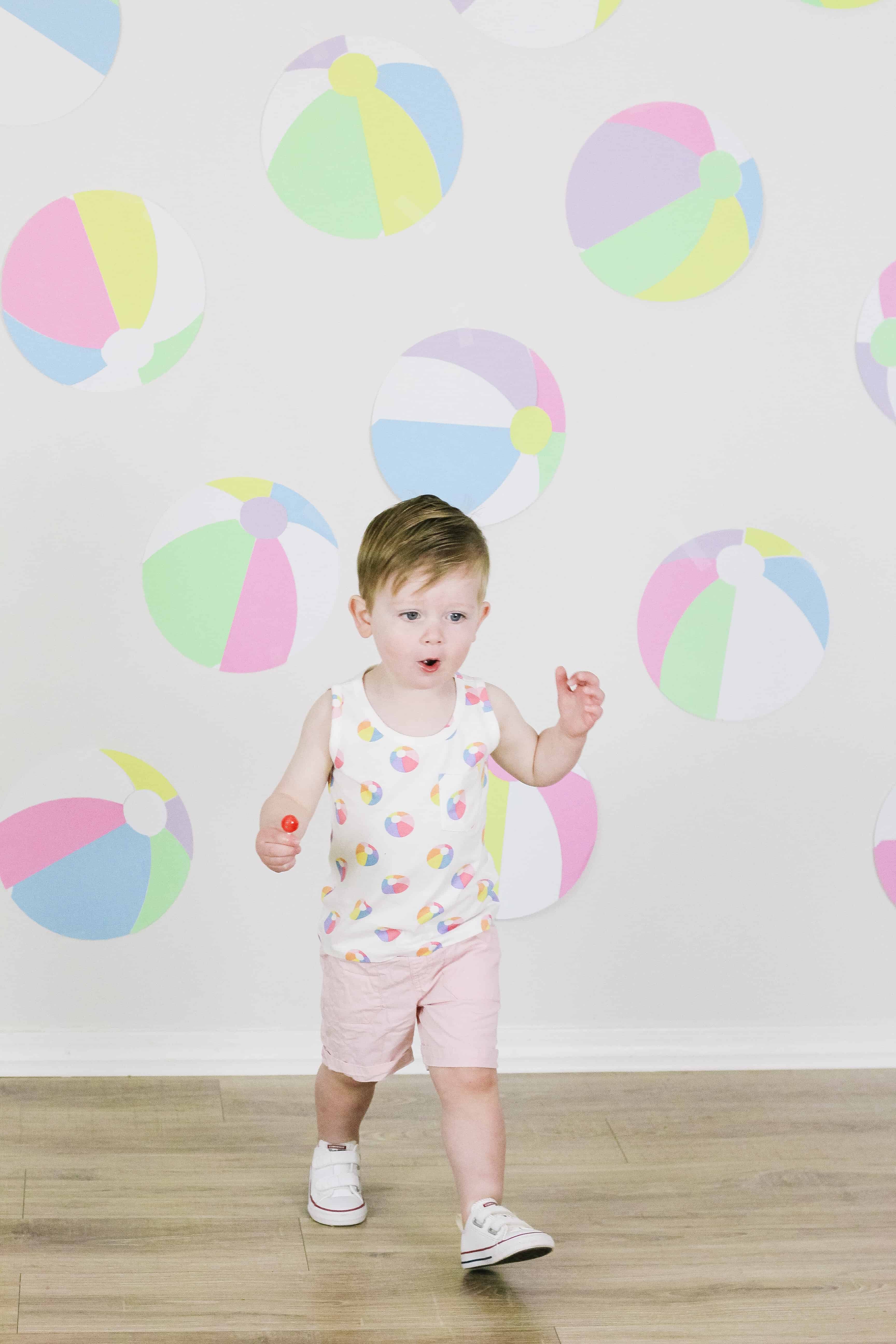 Toddler in beach ball outfit in front of beach ball wall